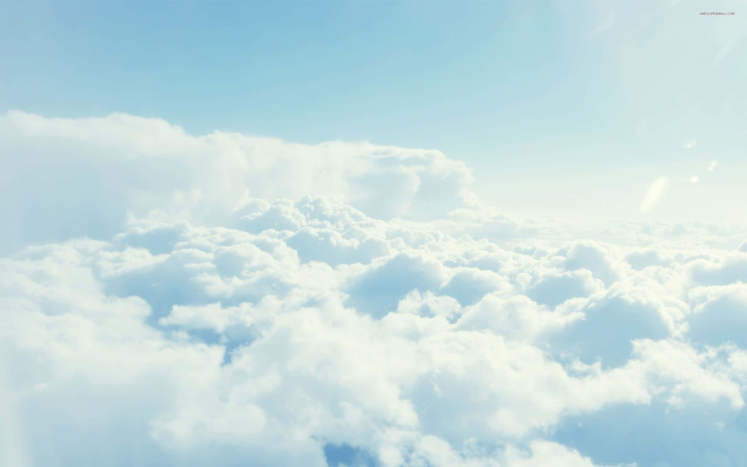 Cloud 桌布 壁紙 — 在清澈藍天下，柔和的陽光穿透蓬鬆的白雲之上，一片寧靜的景色。
