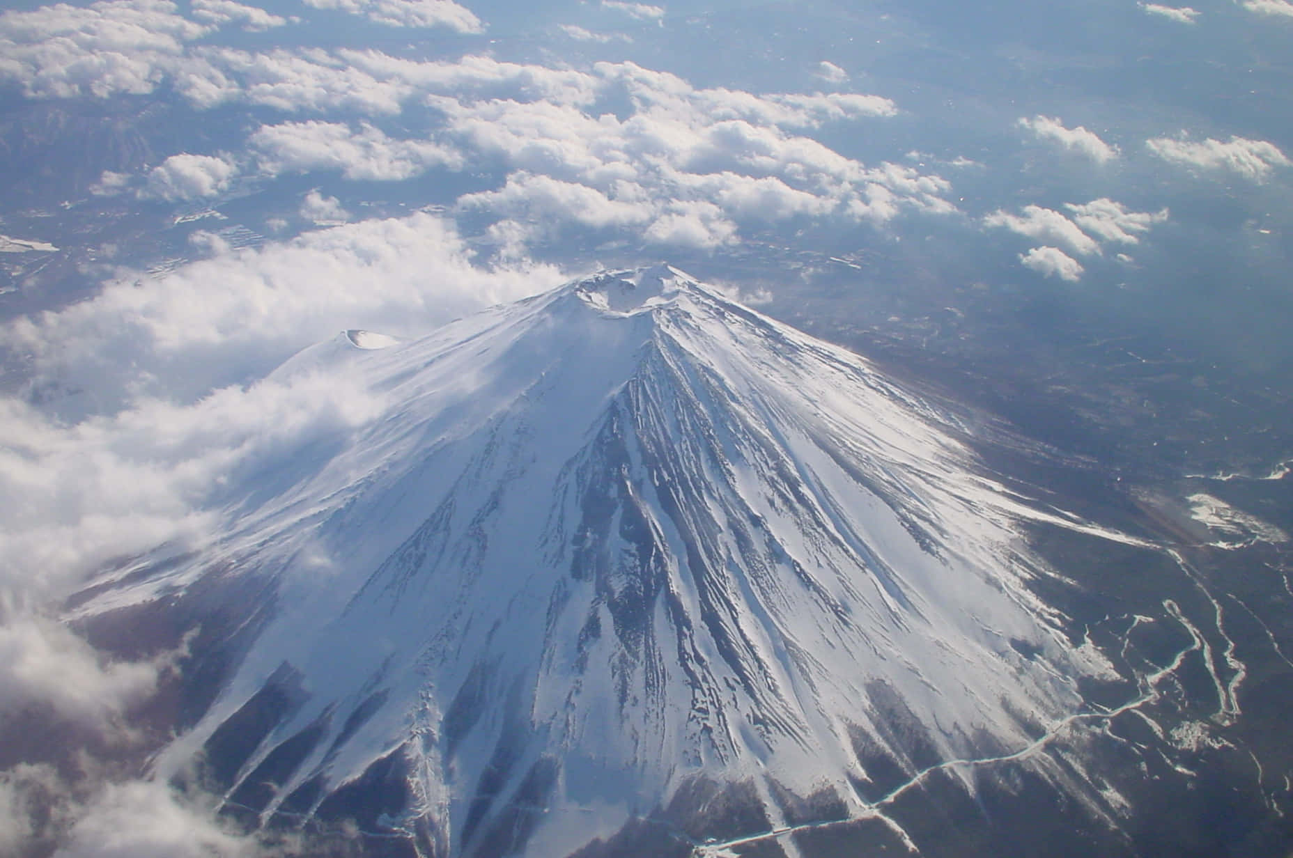 Mt Fuji 桌布 壁紙 — 在清澈藍天下，白雪覆蓋的富士山穿過蓬鬆白雲的鳥瞰圖。