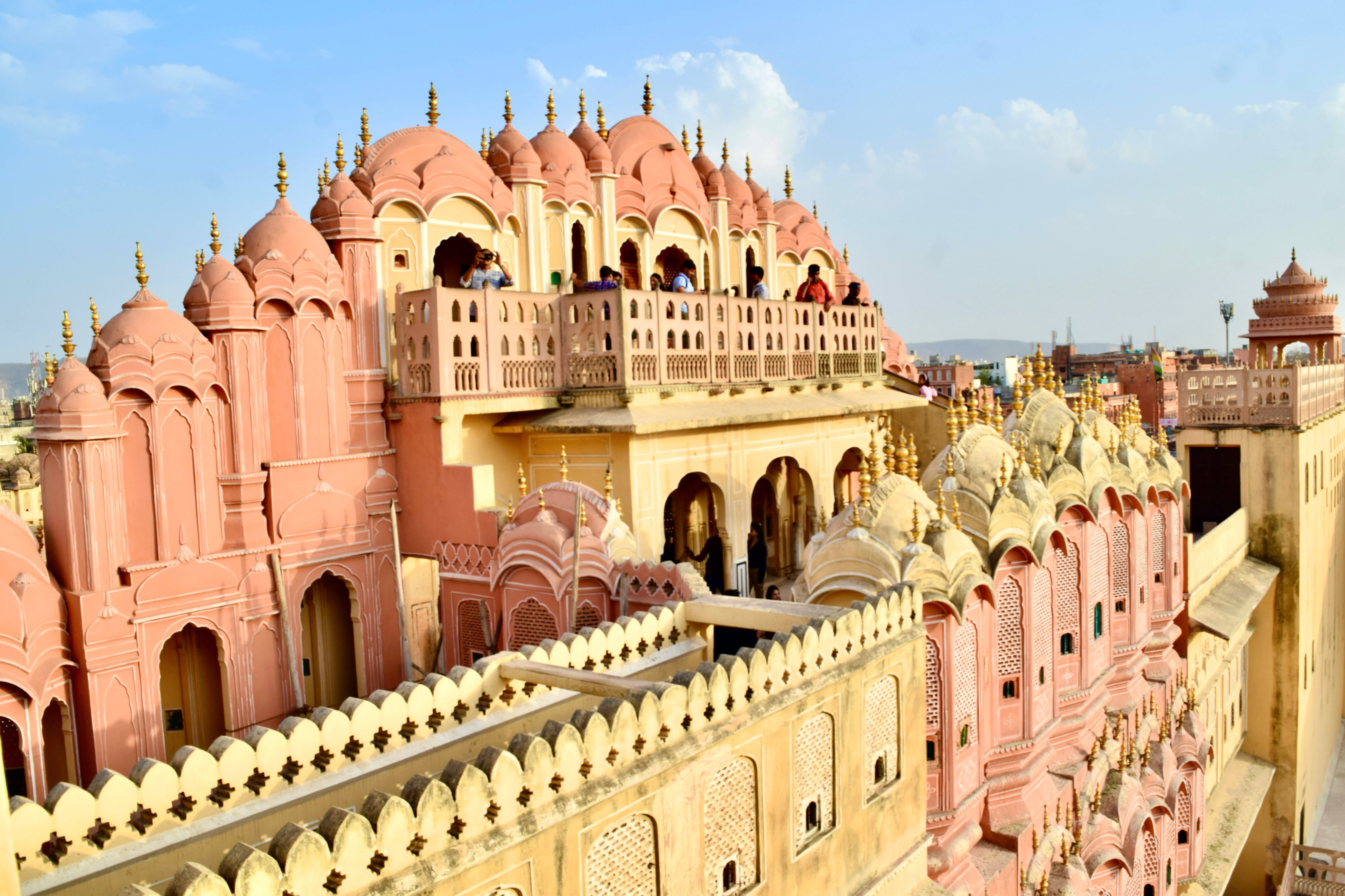 印度 桌布 壁紙 — 在清澈藍天下，雄偉的粉紅色風之宮殿（Hawa Mahal）的鳥瞰圖，擁有精緻的陽台和金色尖塔。