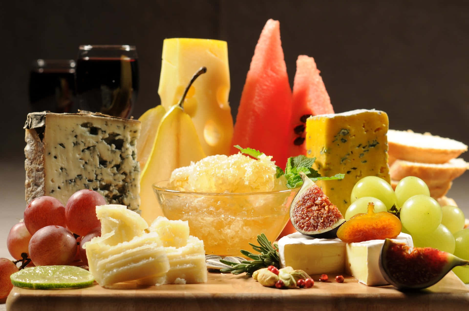 Food And Beverage 桌布 壁紙 — 在溫暖燈光下，一個豪華的熟食拼盤展示了各式起司、水果、麵包和葡萄酒。