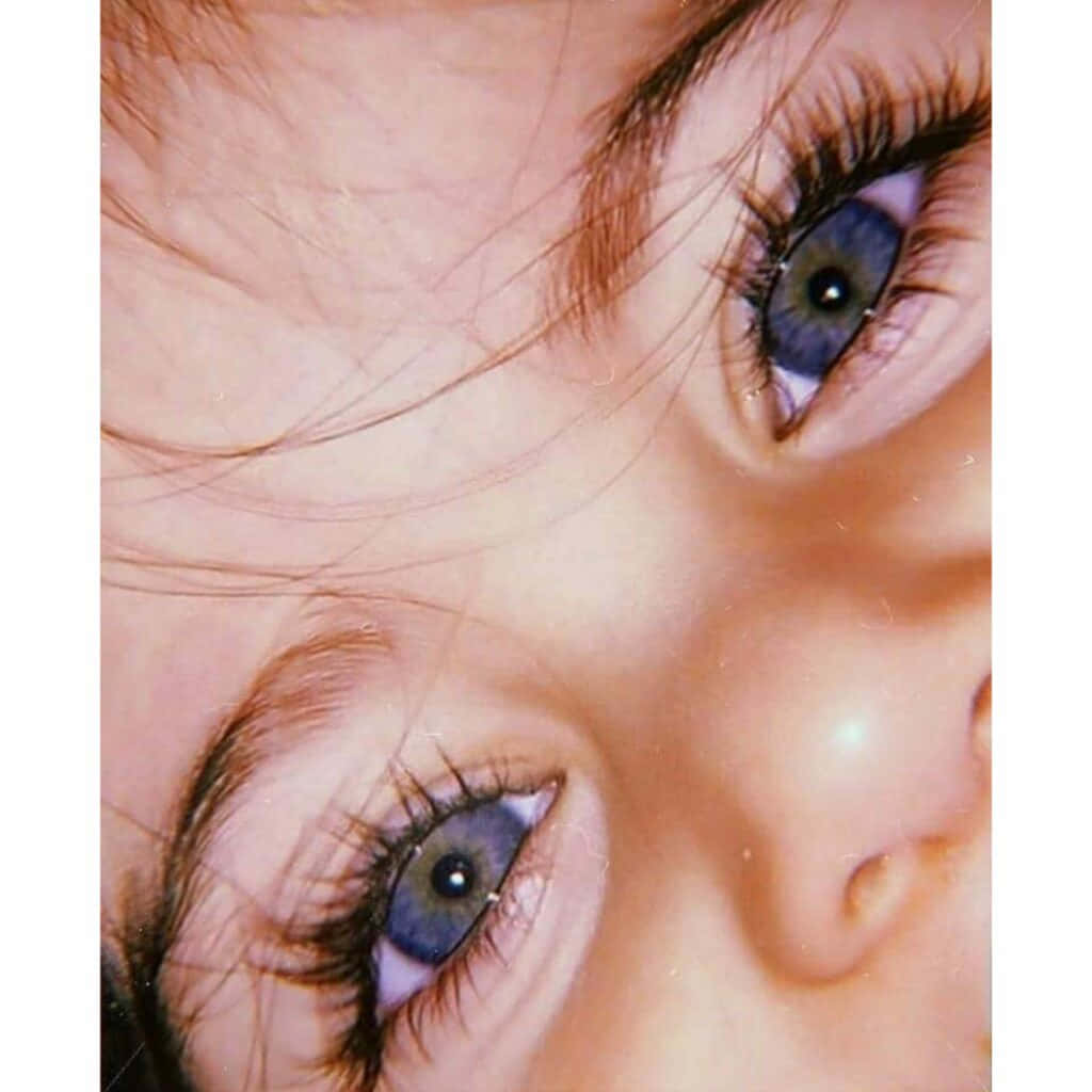 Aesthetic Cute Profile 桌布 壁紙 — 在溫暖燈光下，兒童明亮藍眼睛的特寫，長睫毛和柔軟肌膚。