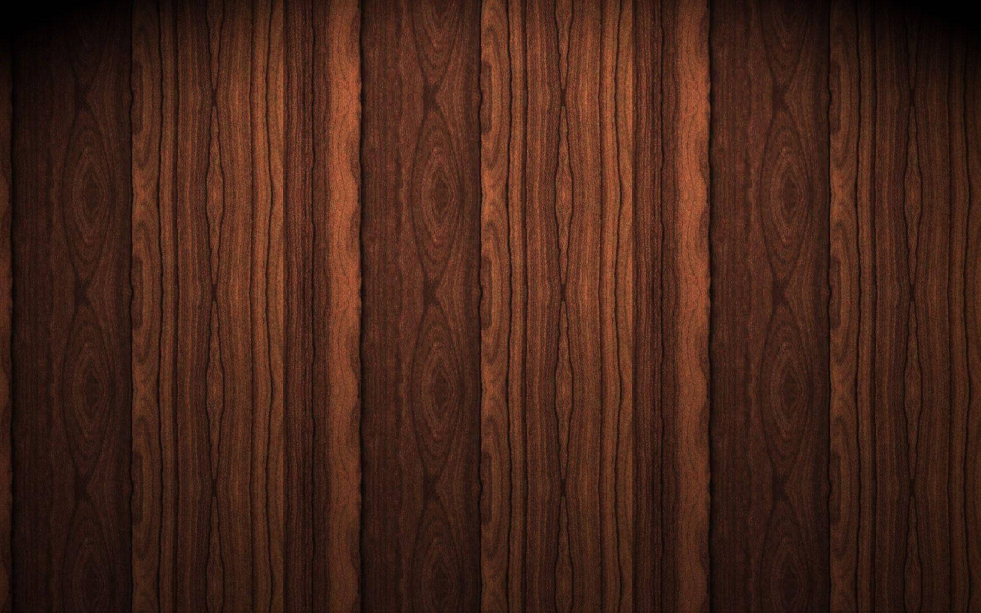 Wood Texture 桌布 壁紙 — 在溫暖燈光下，帶有垂直紋理圖案和細微節疤的濃郁深棕色木板。