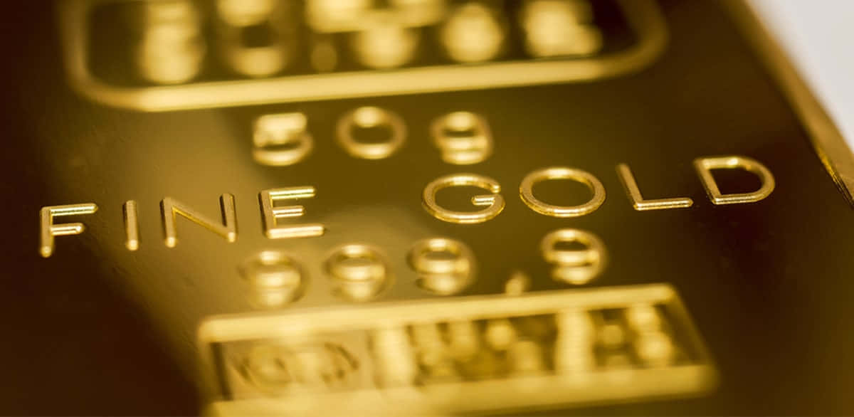 Gold Bar 桌布 壁紙 — 在溫暖燈光下，閃閃發光的金條上刻有「FINE GOLD 999.9」字樣的近距離特寫。