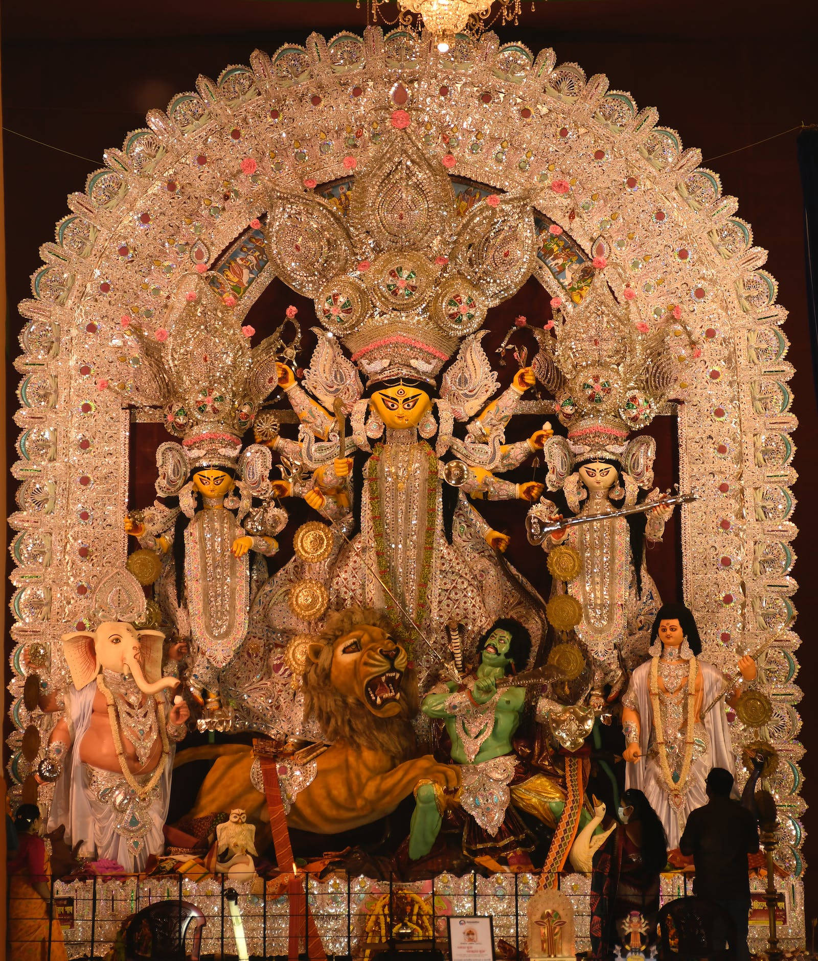 maa durga 桌布 壁紙 — 在溫暖的室內燈光下，宏偉華麗的杜爾迦普迦神像被她的侍從和神話生物包圍。
