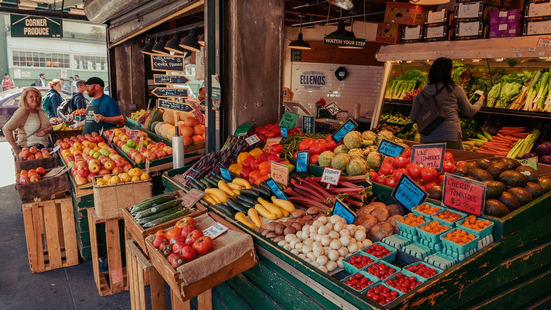 Fruits 桌布 壁紙 — 在溫暖的市場燈光下，色彩繽紛的水果和蔬菜堆滿了充滿活力的農產品攤位。