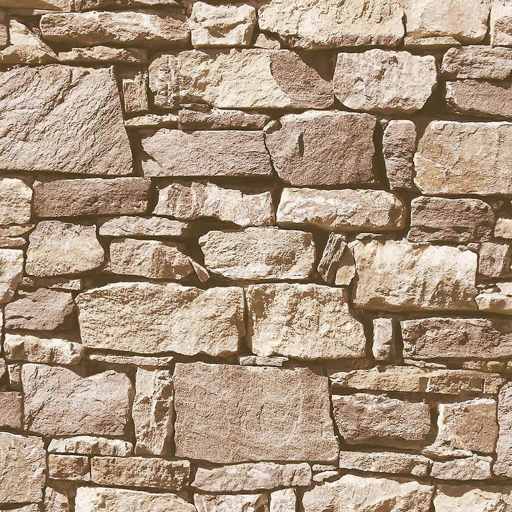 Brick Wall 桌布 壁紙 — 在溫暖陽光下，由不規則形狀的米色和灰色岩石組成的鄉村風格石牆特寫。