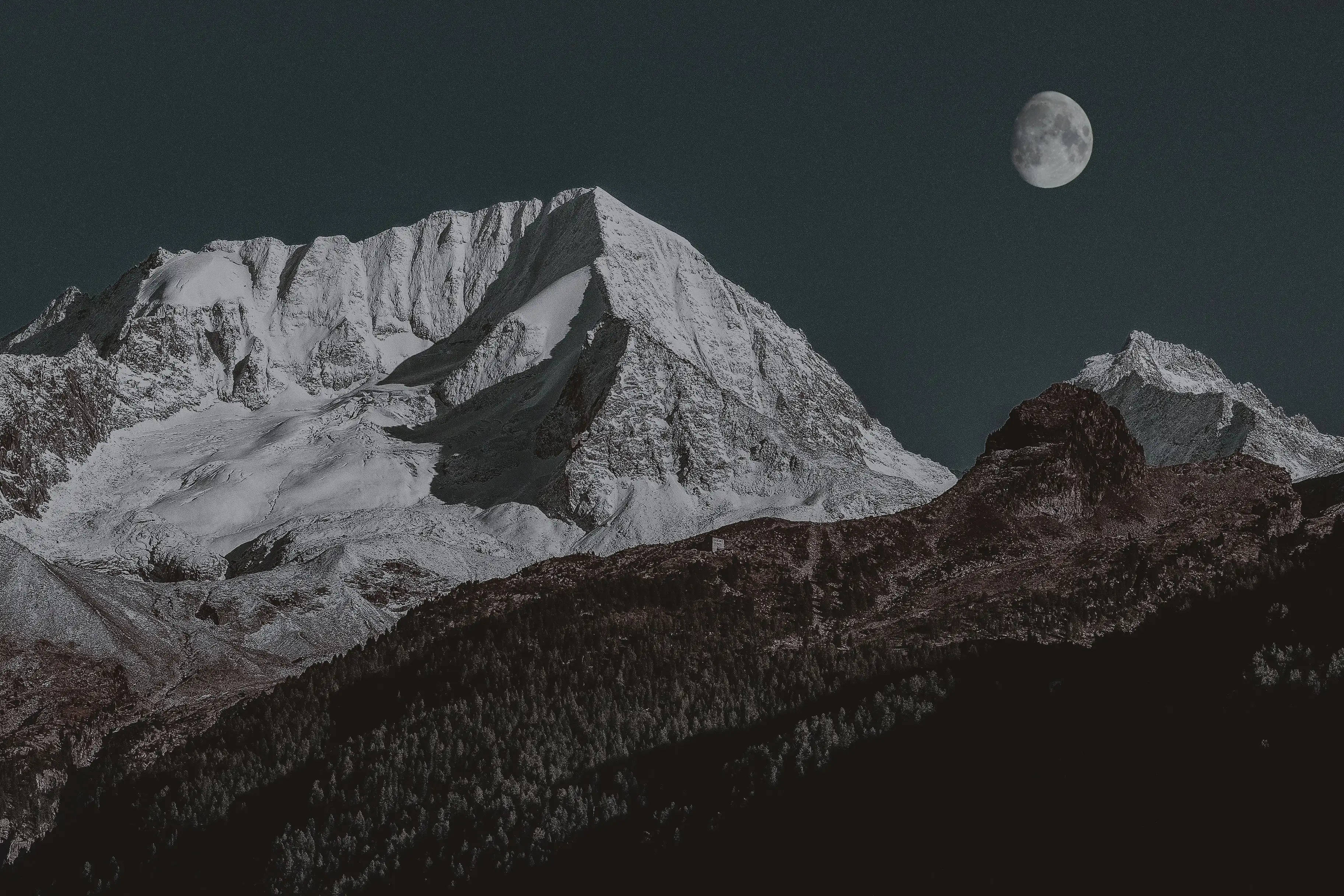 蘋果 桌布 壁紙 — 在漆黑的夜空下，一座積雪的山峰在閃爍的彎月下聳立。