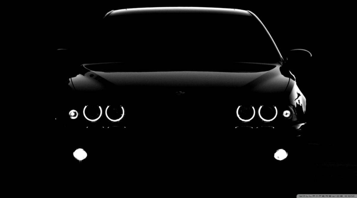 BMW 動圖 桌布 壁紙 — 在漆黑背景下，一輛時尚汽車的輪廓閃爍著明亮的圓形車頭燈。
