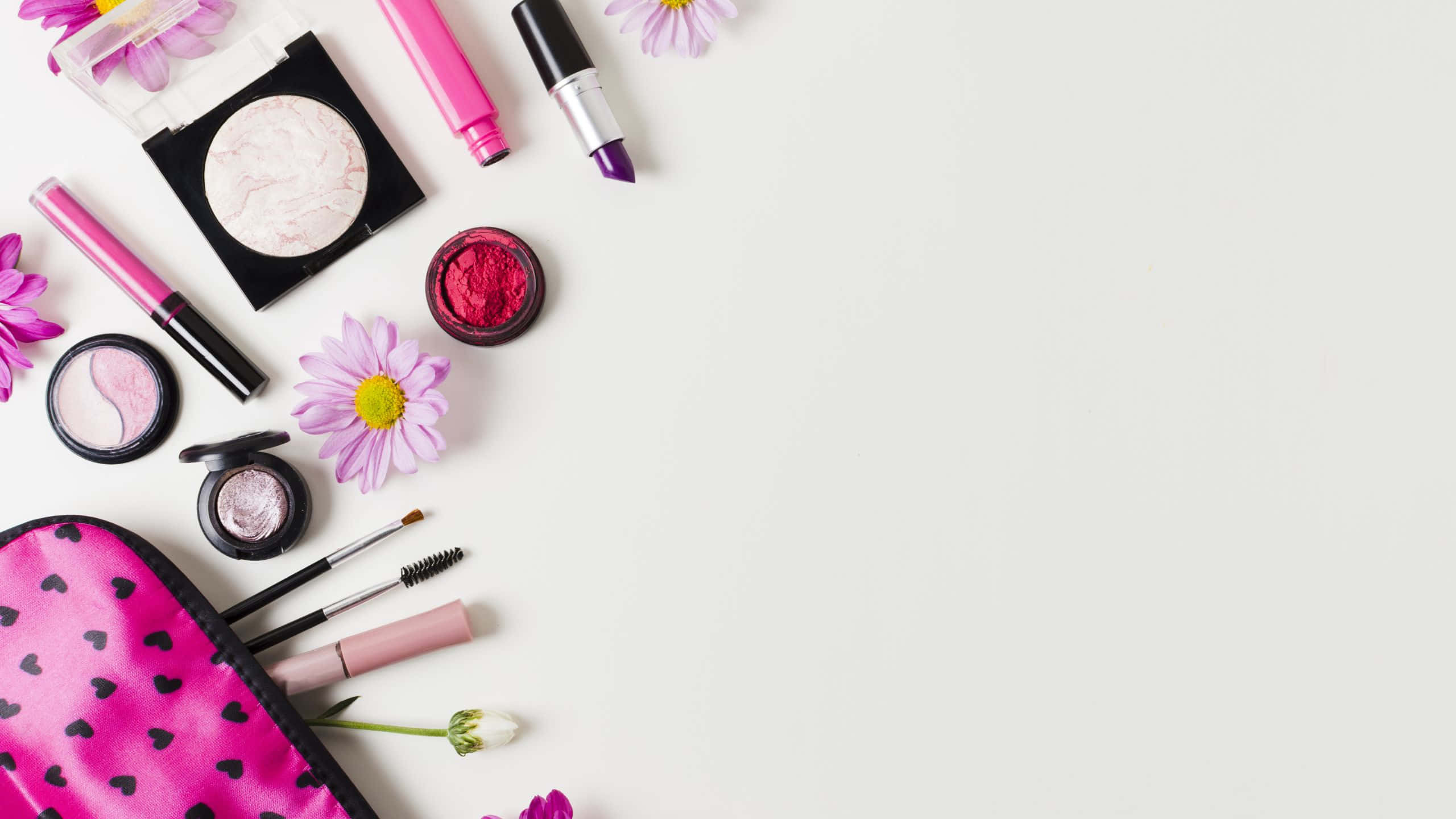 girly pink aesthetic 桌布 壁紙 — 在潔白表面上平鋪擺放充滿活力的粉紅色和紫色化妝品及花朵。