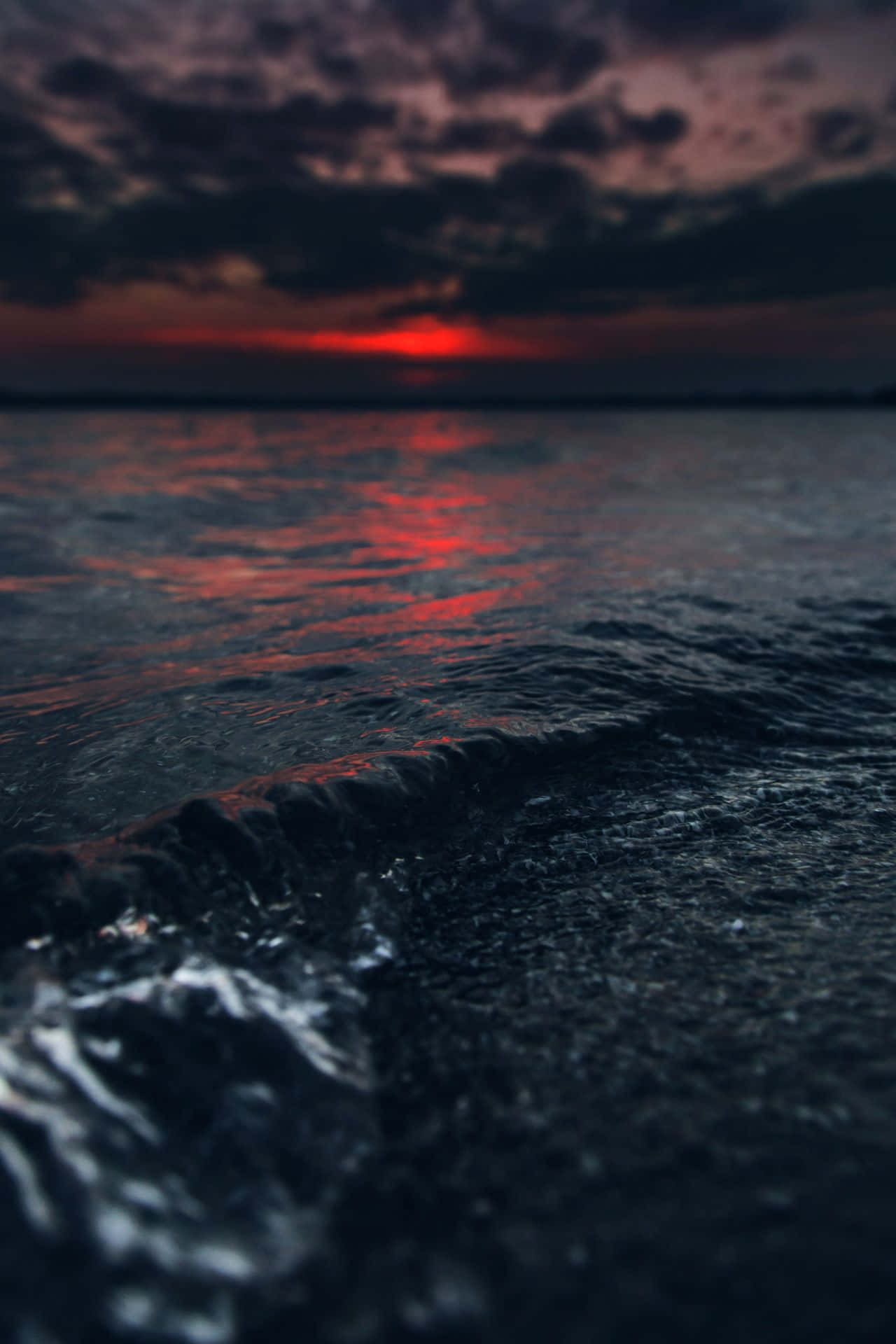 桌布 壁紙 — 在火紅的日落天空和烏雲下，一道戲劇性的海浪翻湧。