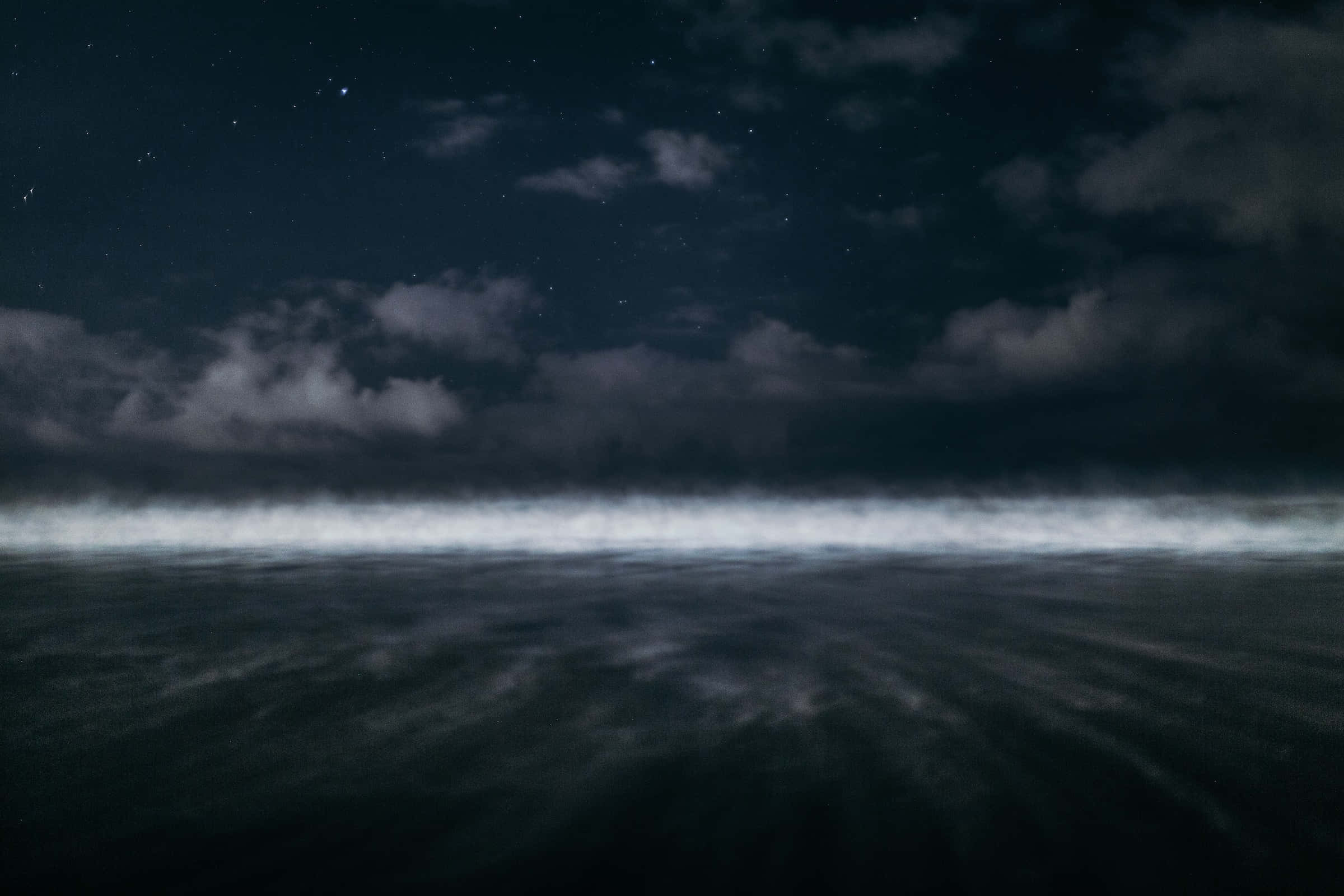 Dark Ocean 桌布 壁紙 — 在無月的天空下，繁星點點的夜空與散落的雲朵飄浮在霧濛濛的黑暗海洋之上。