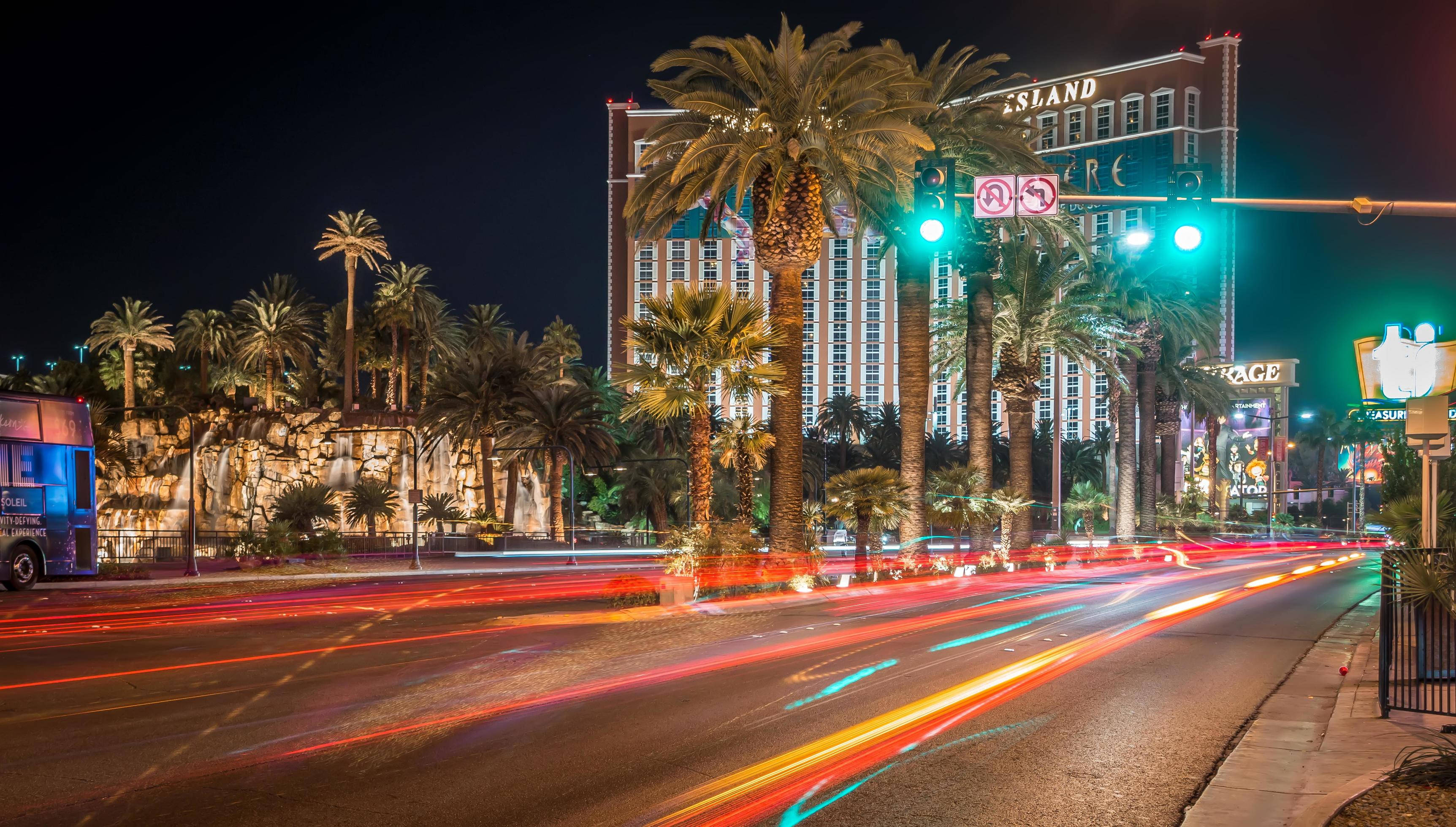 Las Vegas 桌布 壁紙 — 在發光的棕櫚樹和高聳的飯店招牌下，充滿活力的光跡劃過拉斯維加斯夜晚繁忙的街道。