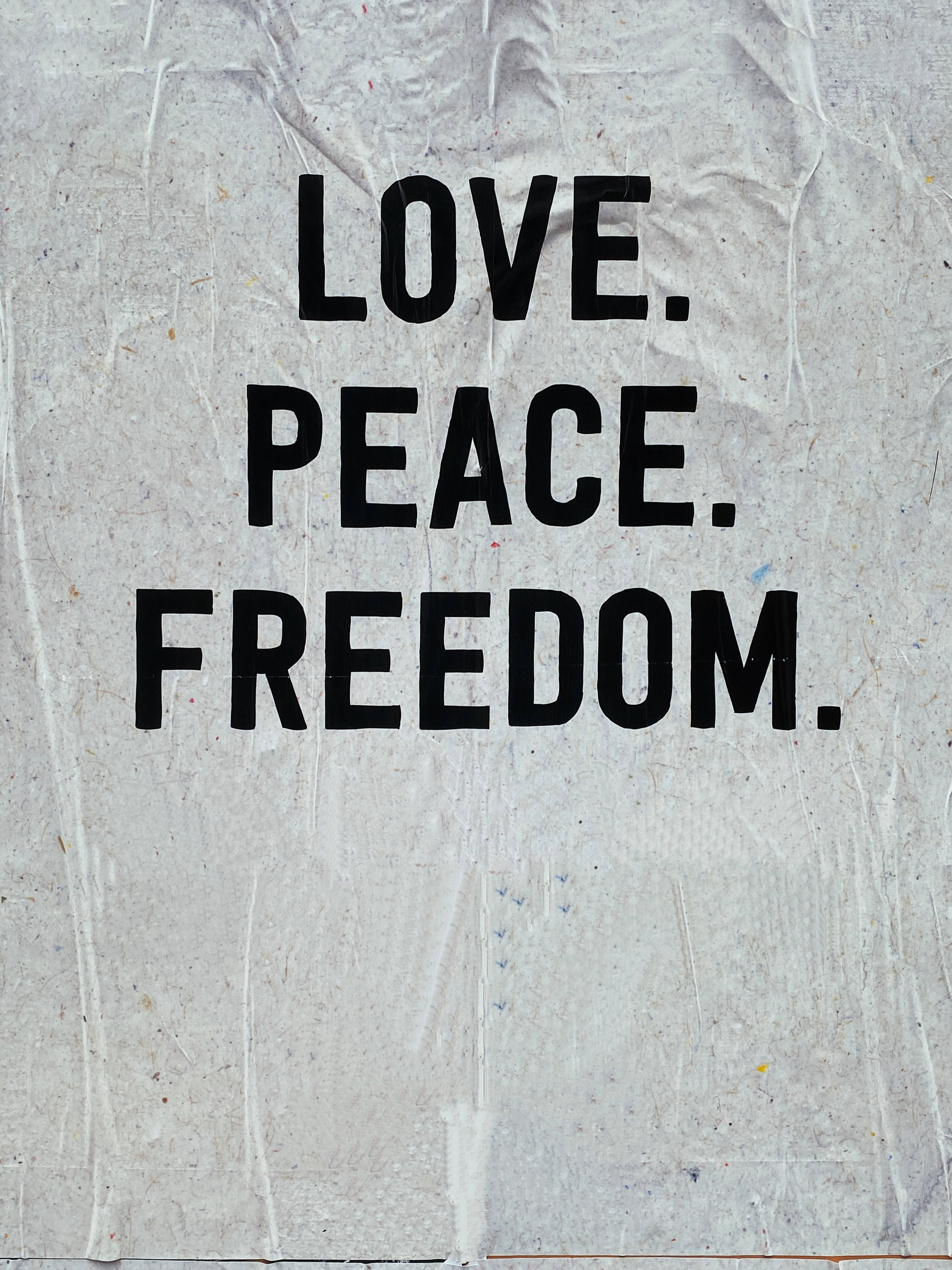 和平 桌布 壁紙 — 在皺紋紋理白色紙張背景上，粗體黑色文字寫著 LOVE PEACE FREEDOM。
