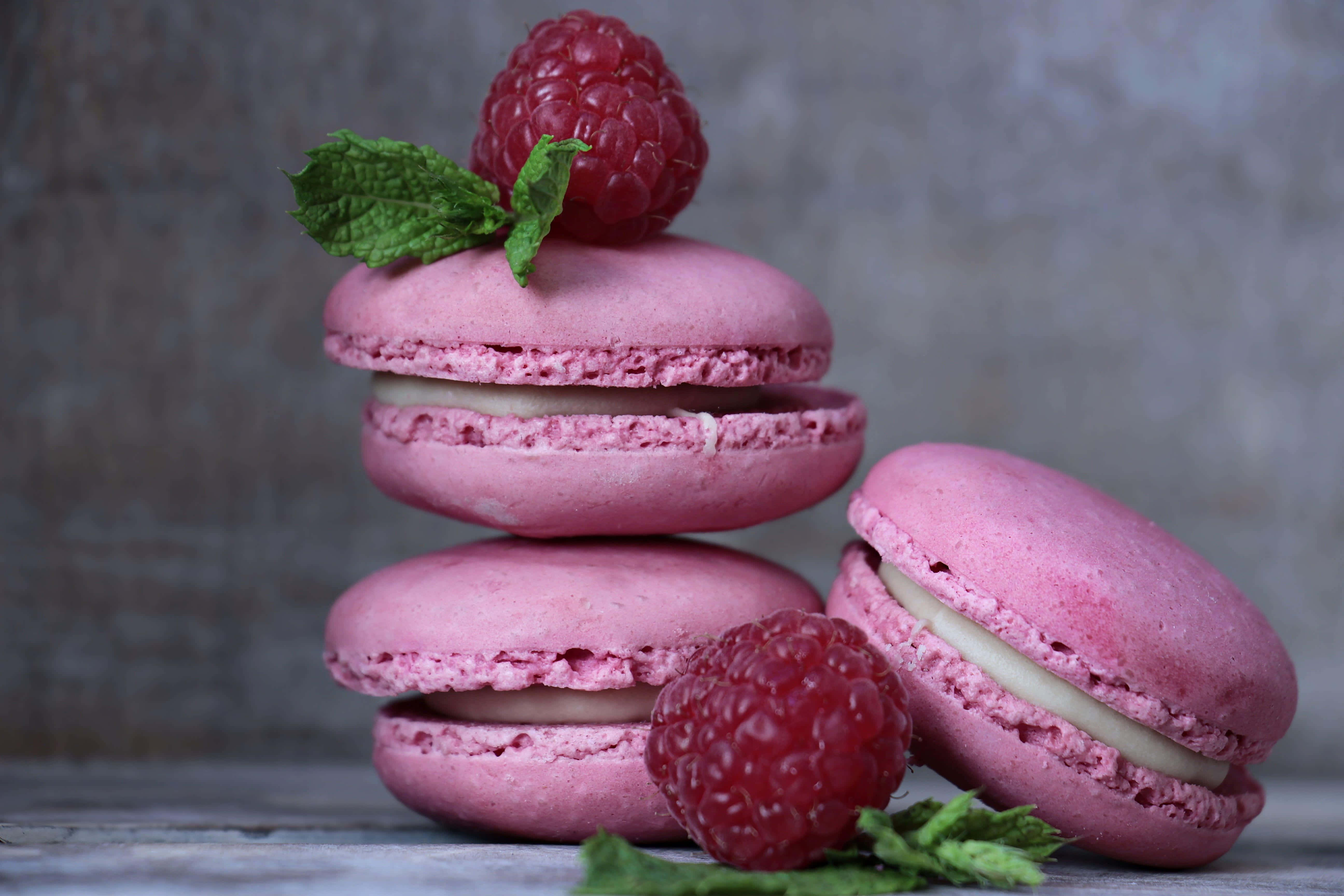 Macaron 桌布 壁紙 — 在紋理灰色背景上，堆疊的粉紅色覆盆子馬卡龍，上面放有新鮮漿果和薄荷。
