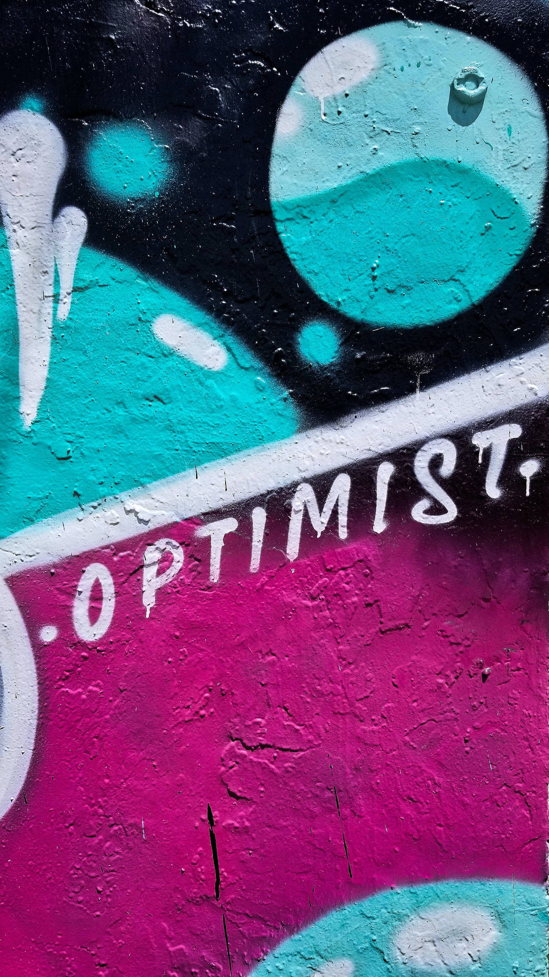 塗鴉壁畫，以青綠色和洋紅色在粗糙牆壁上拼寫「optimist」。