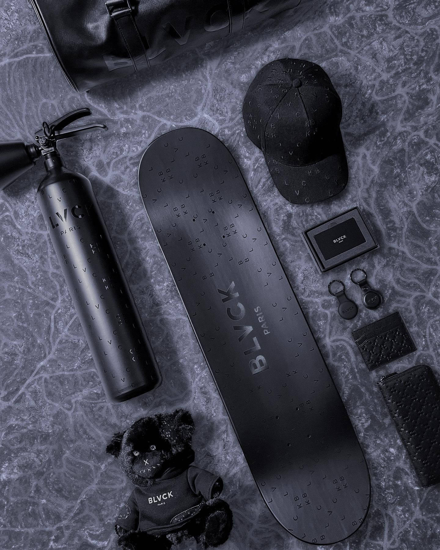 Blvck Paris 桌布 壁紙 — 在紋理石面上排列的單色奢華黑色滑板裝備及配件平鋪圖。
