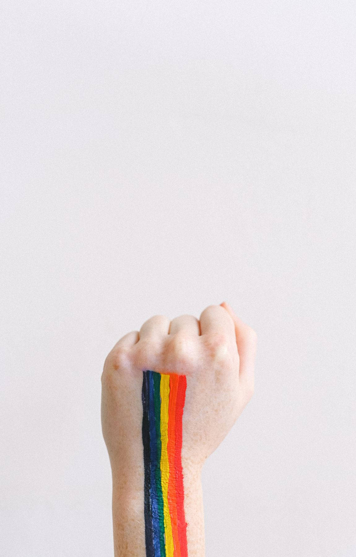 Subtle Lgbt 桌布 壁紙 — 在純白色背景上，前臂上繪有鮮豔彩虹條紋的舉起拳頭。