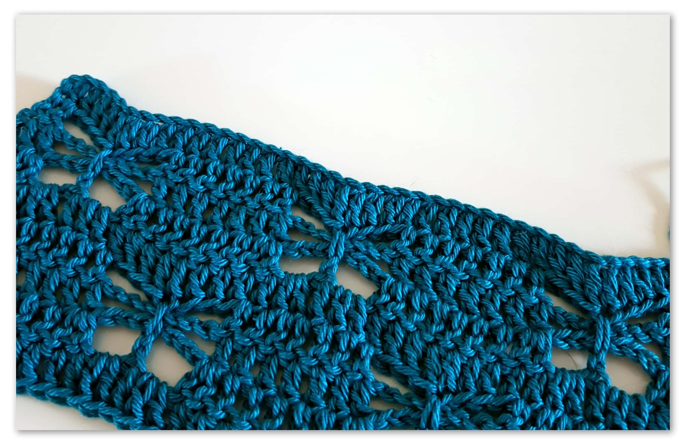 Butterfly Stitch 桌布 壁紙 — 在純白色背景上，帶有複雜蕾絲圖案的青綠色鉤針編織布料的特寫。