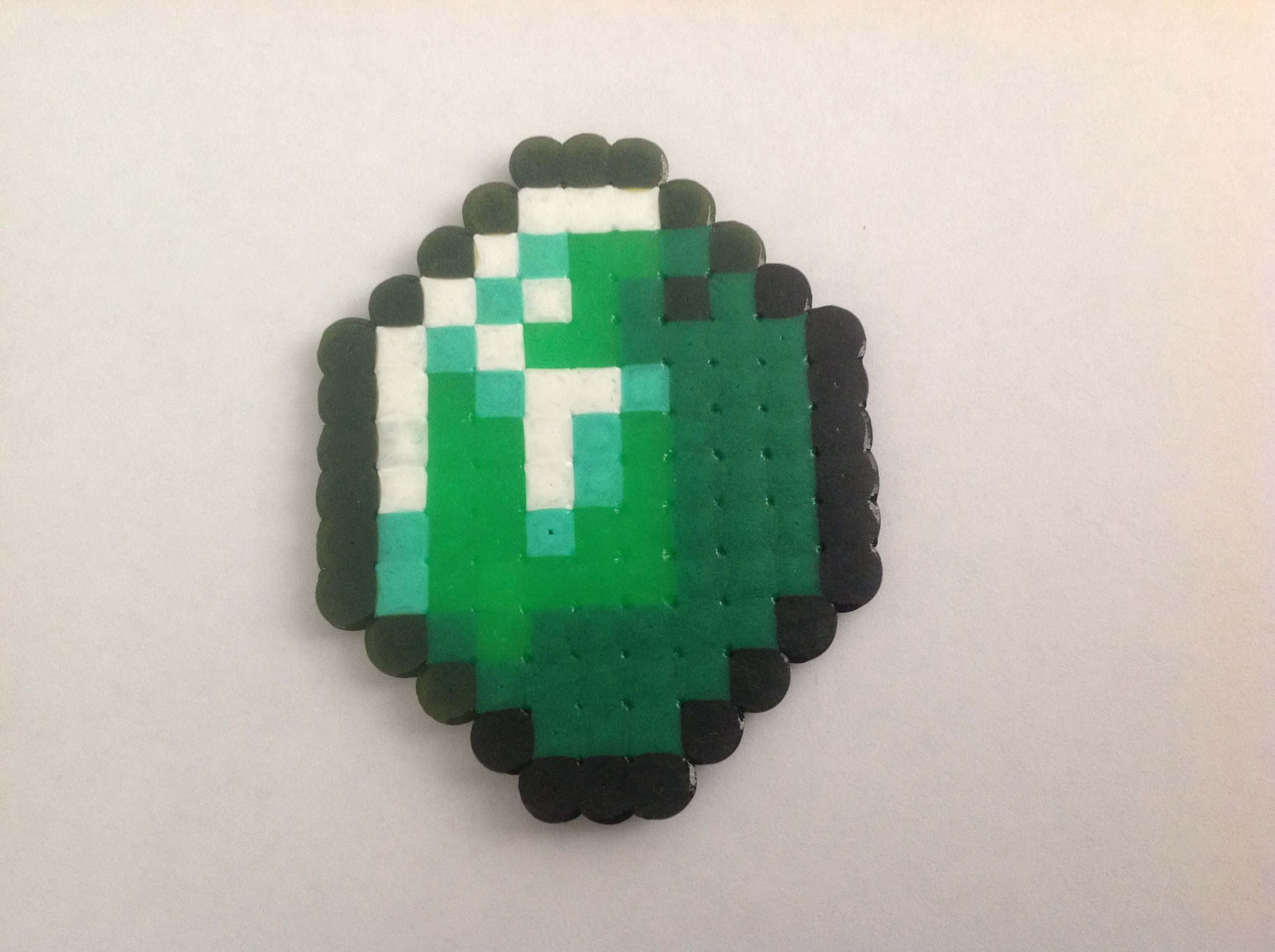 Minecraft Emeralds 桌布 壁紙 — 在純白色背景上，用拼豆製成的像素化綠色鑽石胸針。