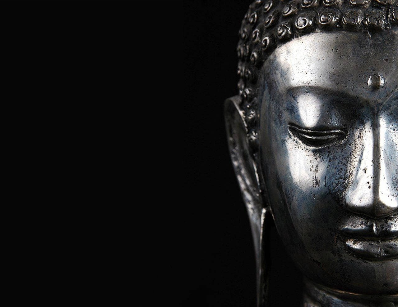 black buddha 桌布 壁紙 — 在純黑背景上，柔和燈光突顯寧靜銀色佛像頭像的平和表情特寫。