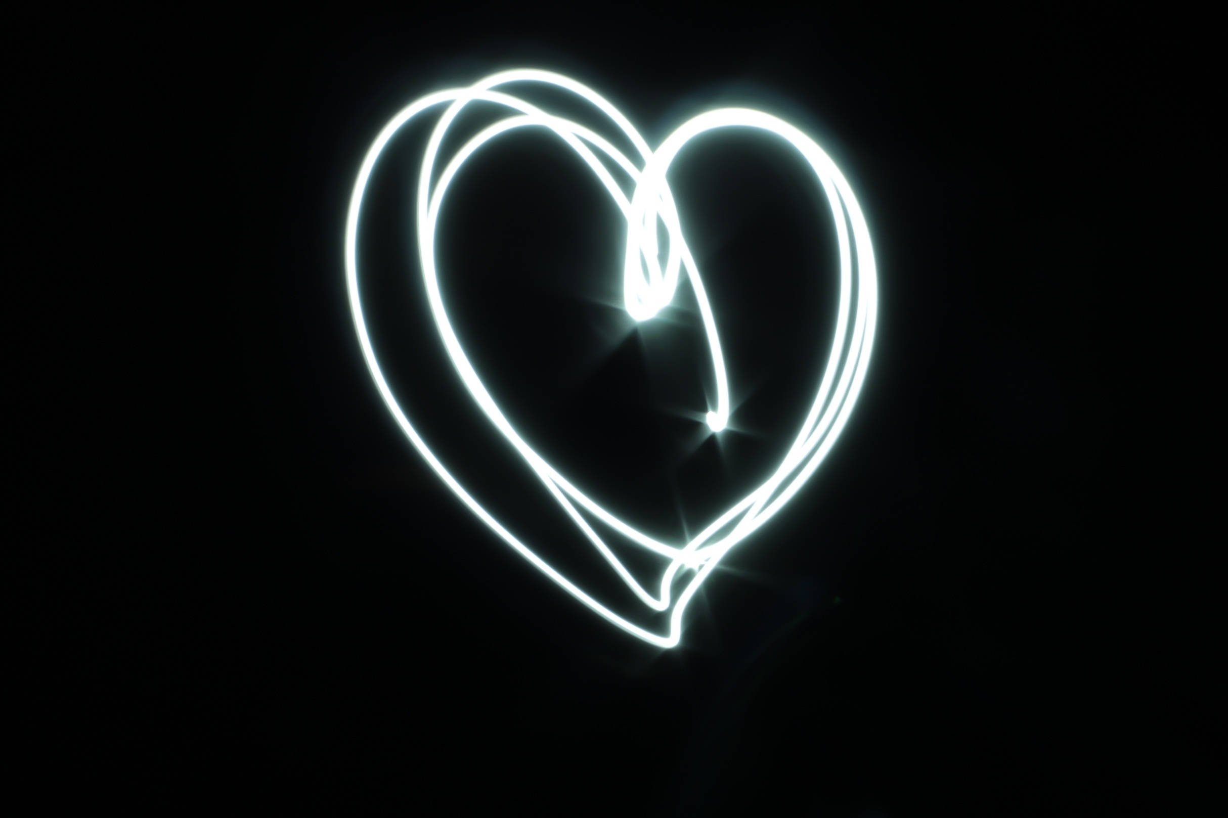 Black Heart Aesthetic 桌布 壁紙 — 在純黑背景上以光軌繪製的發光白色心形。