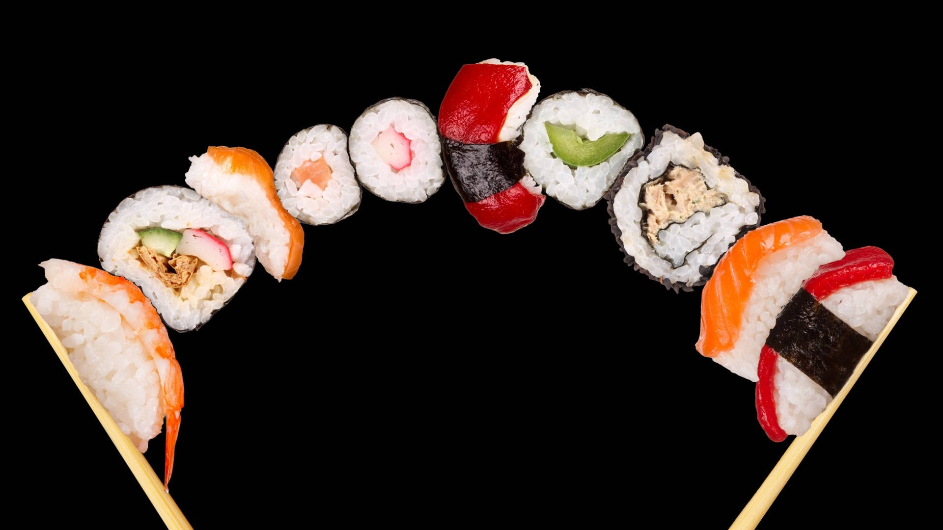 Sushi 桌布 壁紙 — 在純黑背景下，筷子夾著各式壽司卷，形成一道鮮豔的弧線。