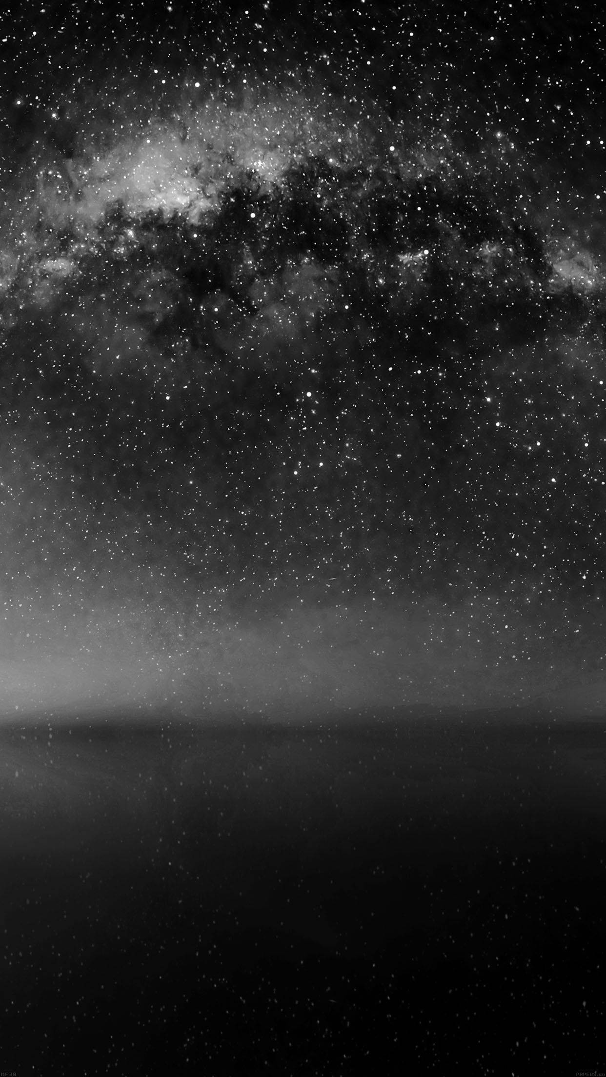 Stars 桌布 壁紙 — 在繁星滿天的天空下，銀河系在霧氣瀰漫的地平線上拱起，構成一個令人屏息的黑白景觀。