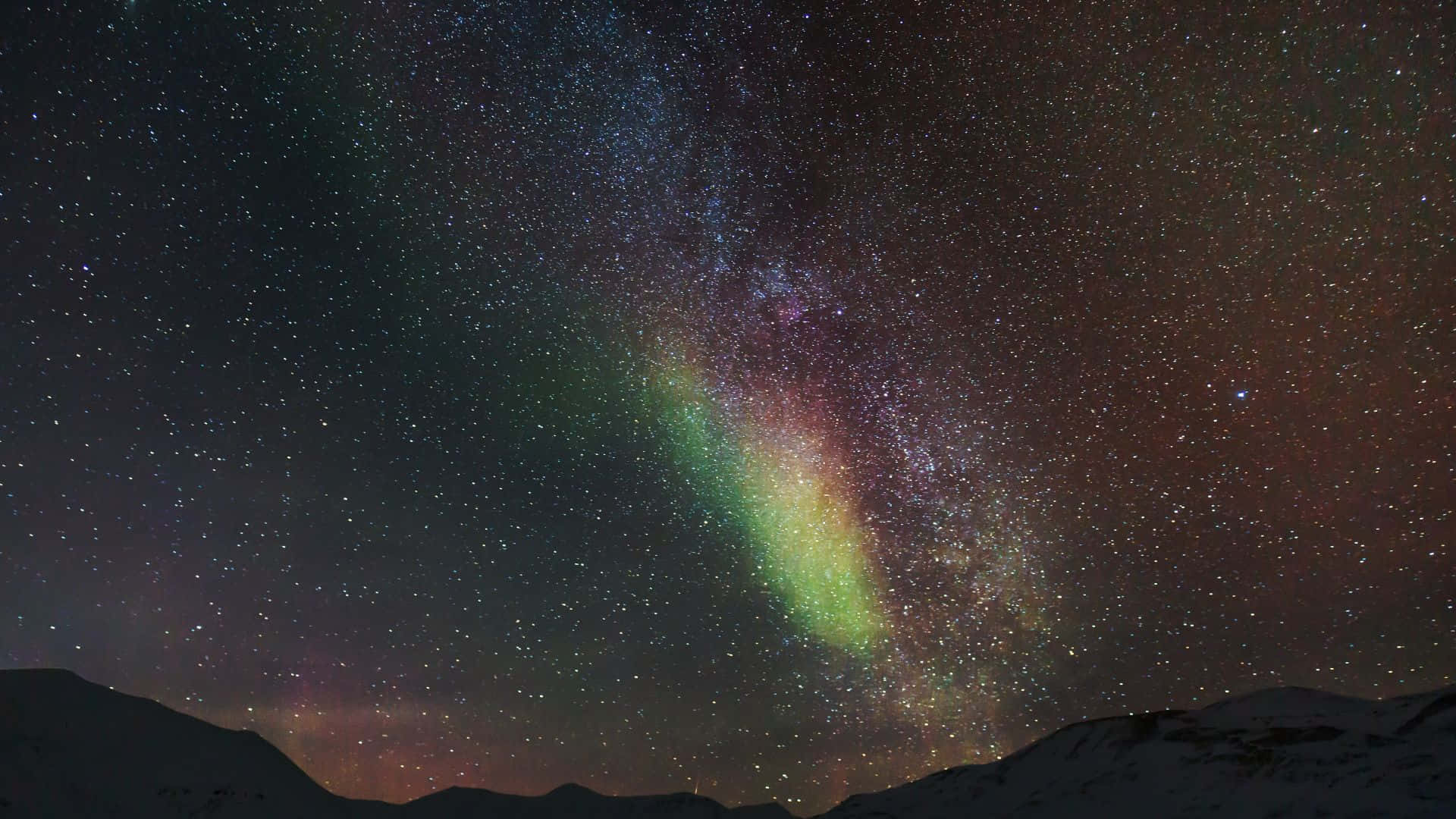 極光 桌布 壁紙 — 在繁星點點的夜空下，生動的極光在積雪的山峰上舞動。