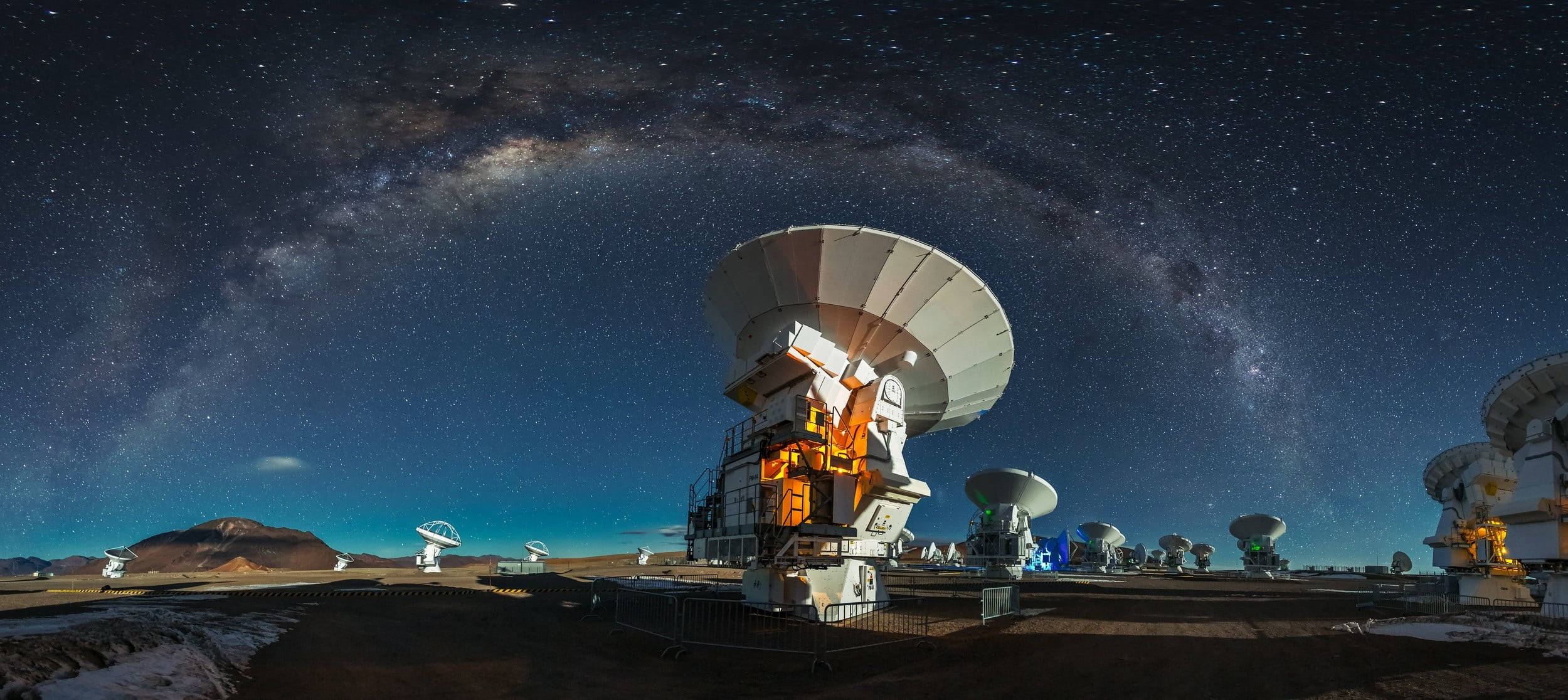 Chile 桌布 壁紙 — 在繁星點點的夜空下，銀河拱掛頭頂的電波望遠鏡全景視圖。