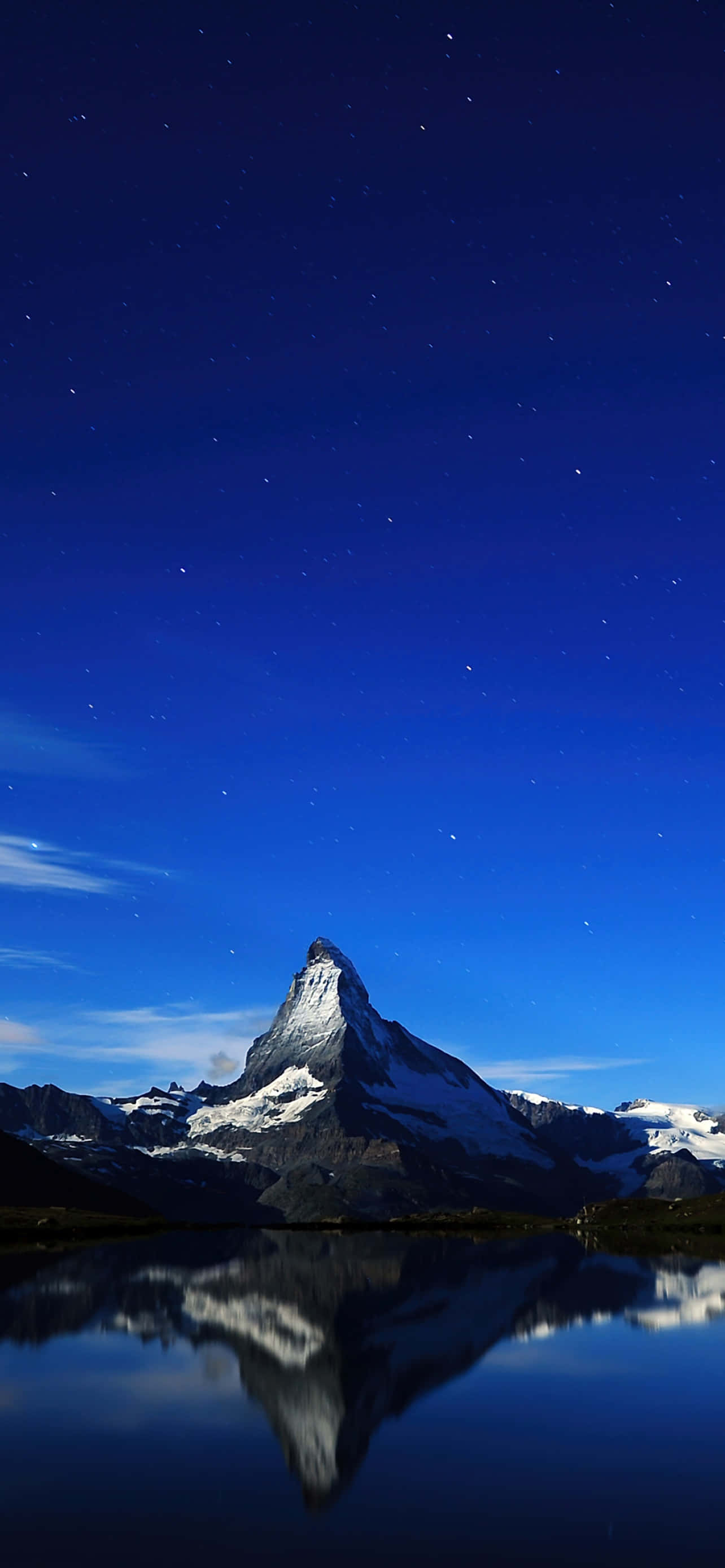Starry Sky 桌布 壁紙 — 在繁星點點的夜空下，雄偉的雪山山峰完美地倒映在下方平靜的湖面上。
