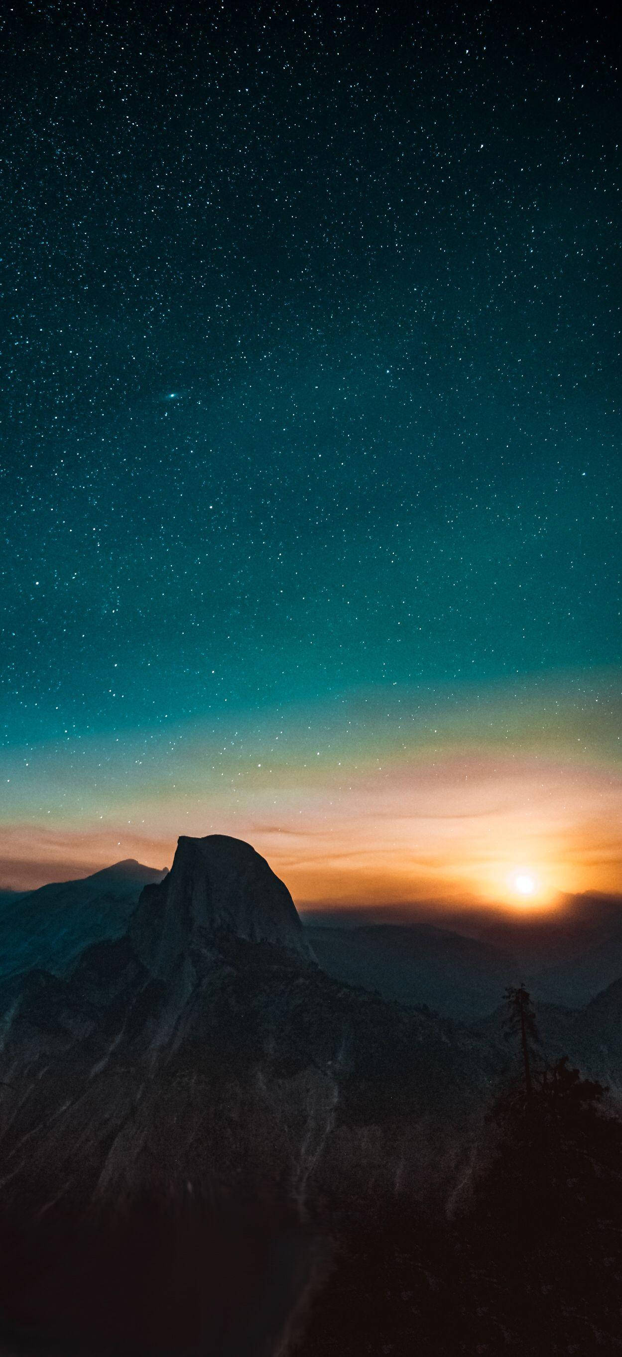iPhone 桌布 壁紙 — 在繁星點點的暮色天空下，雄偉的山脈輪廓，地平線上有閃耀的日落。