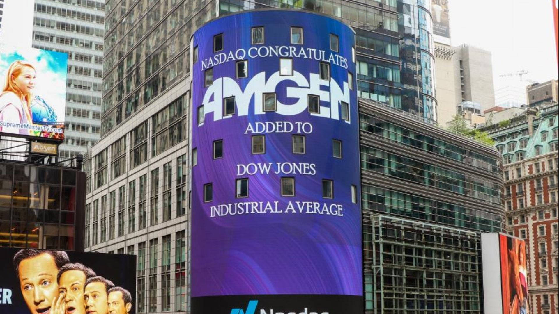 Dow 桌布 壁紙 — 在繁華的市中心，一座高聳的紫色數位廣告看板宣布Amgen加入道瓊工業平均指數，周圍是玻璃摩天大樓。