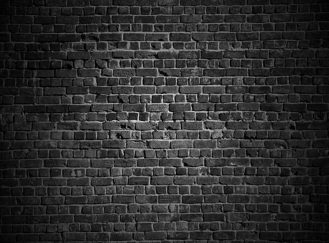 Brick 桌布 壁紙 — 在聚焦聚光燈下，一面光線昏暗的黑色磚牆，帶有紋理灰泥和細微磨損。