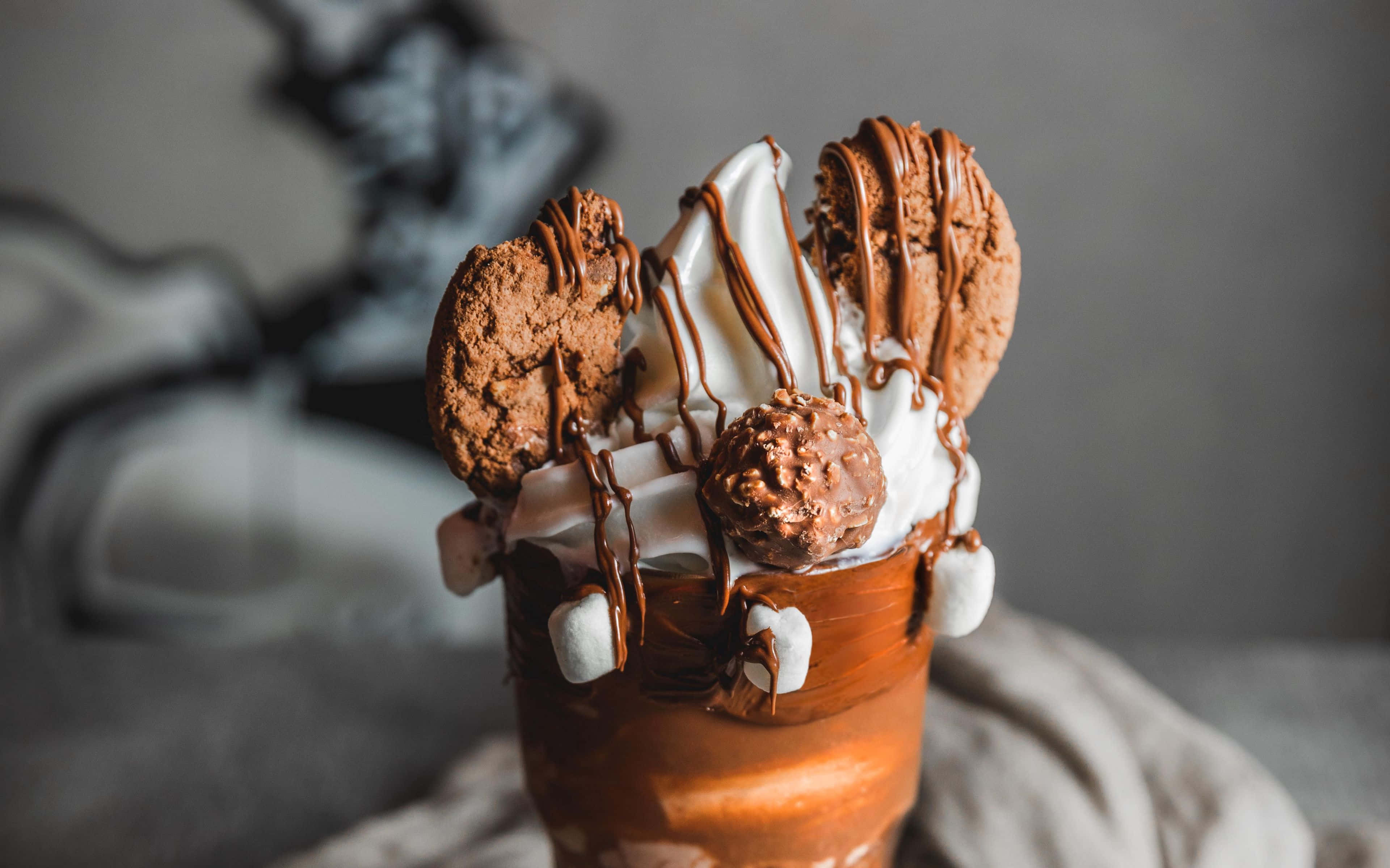 Ice Cream 桌布 壁紙 — 在舒適的環境中，一杯頹廢的熱巧克力，上面有鮮奶油、巧克力醬、棉花糖和巧克力餅乾。