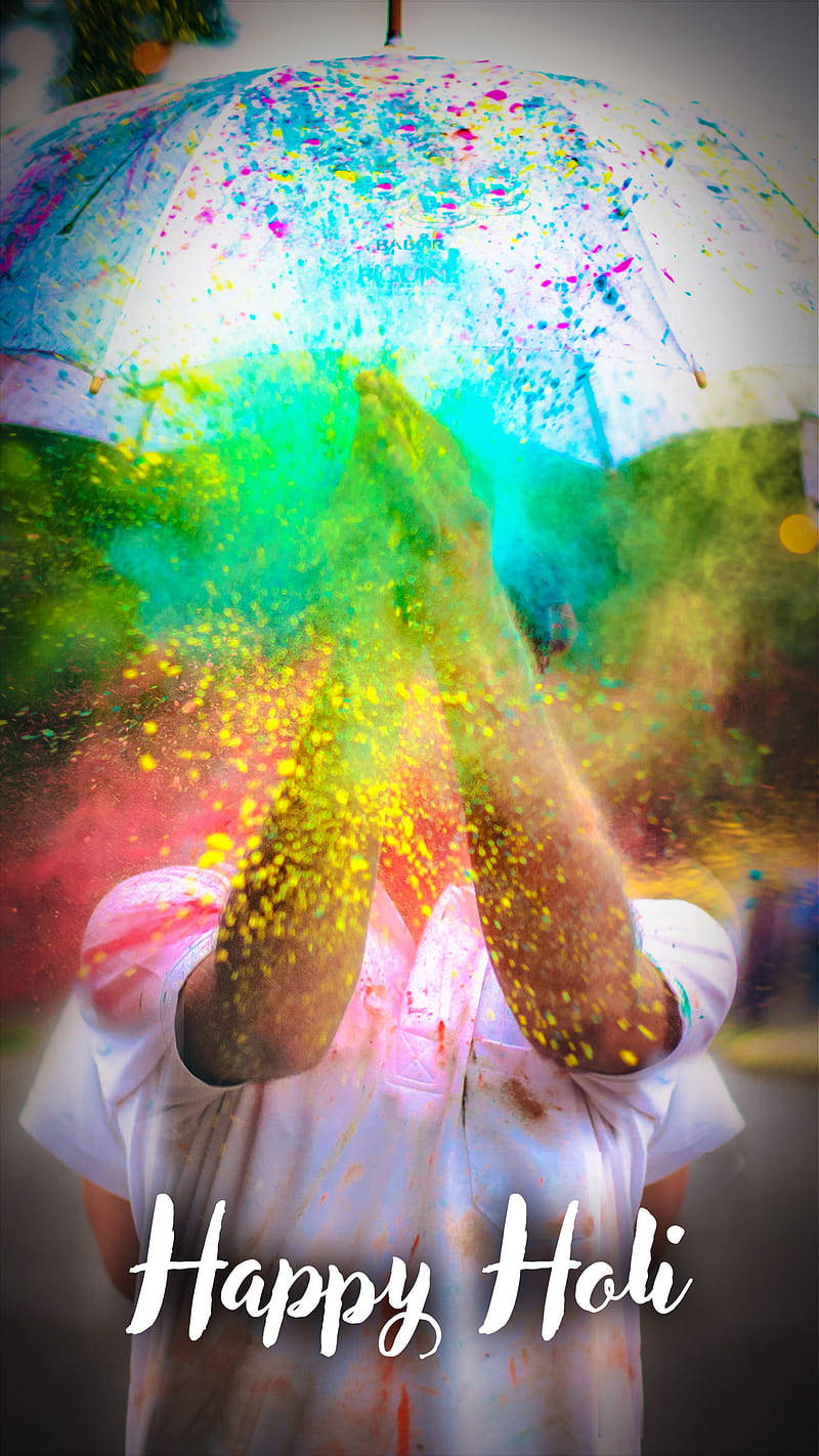 Holi 桌布 壁紙 — 在色彩繽紛的雨傘下，一個人在灑紅節期間歡快地將鮮豔的粉末拋向空中。