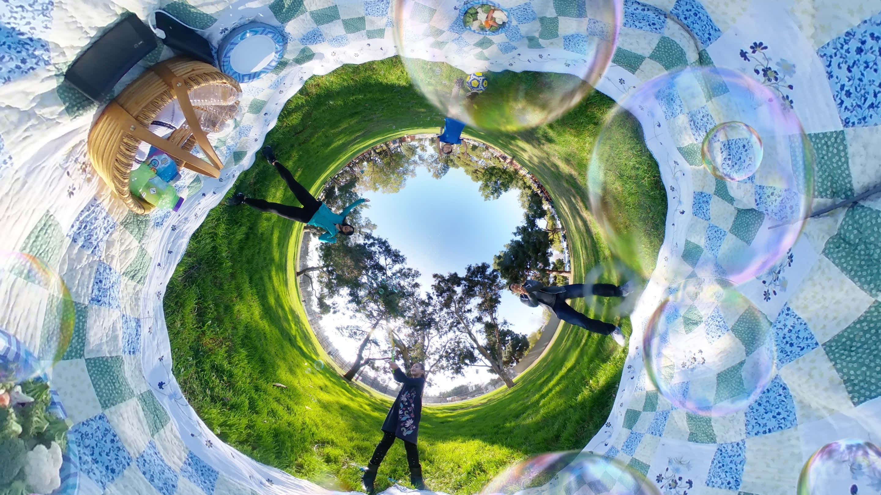 picnic 桌布 壁紙 — 在草地公園的圖案野餐墊上，人們玩巨型肥皂泡的360度魚眼視角。