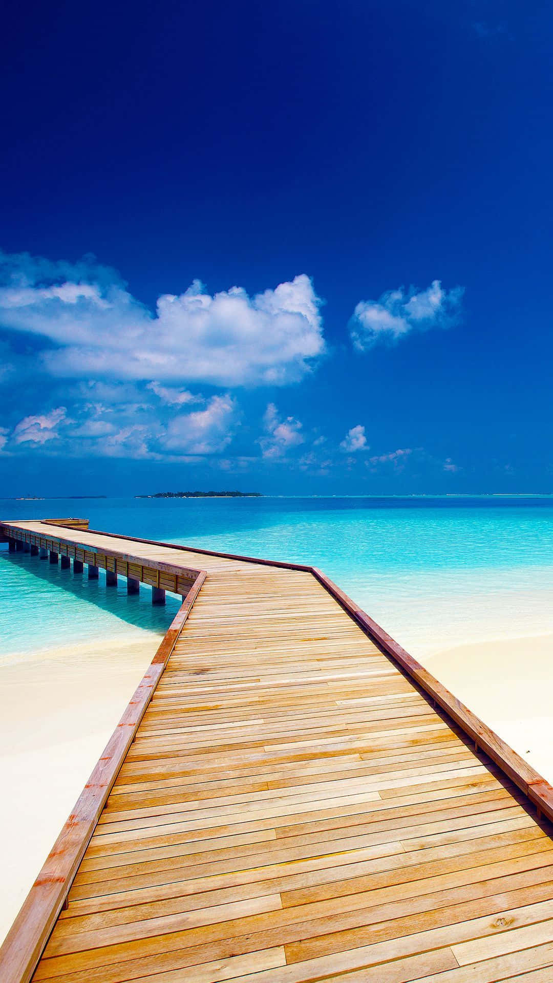 Hi Res Beach 桌布 壁紙 — 在藍天白雲下，一條木製碼頭延伸至清澈的碧綠海水之中。