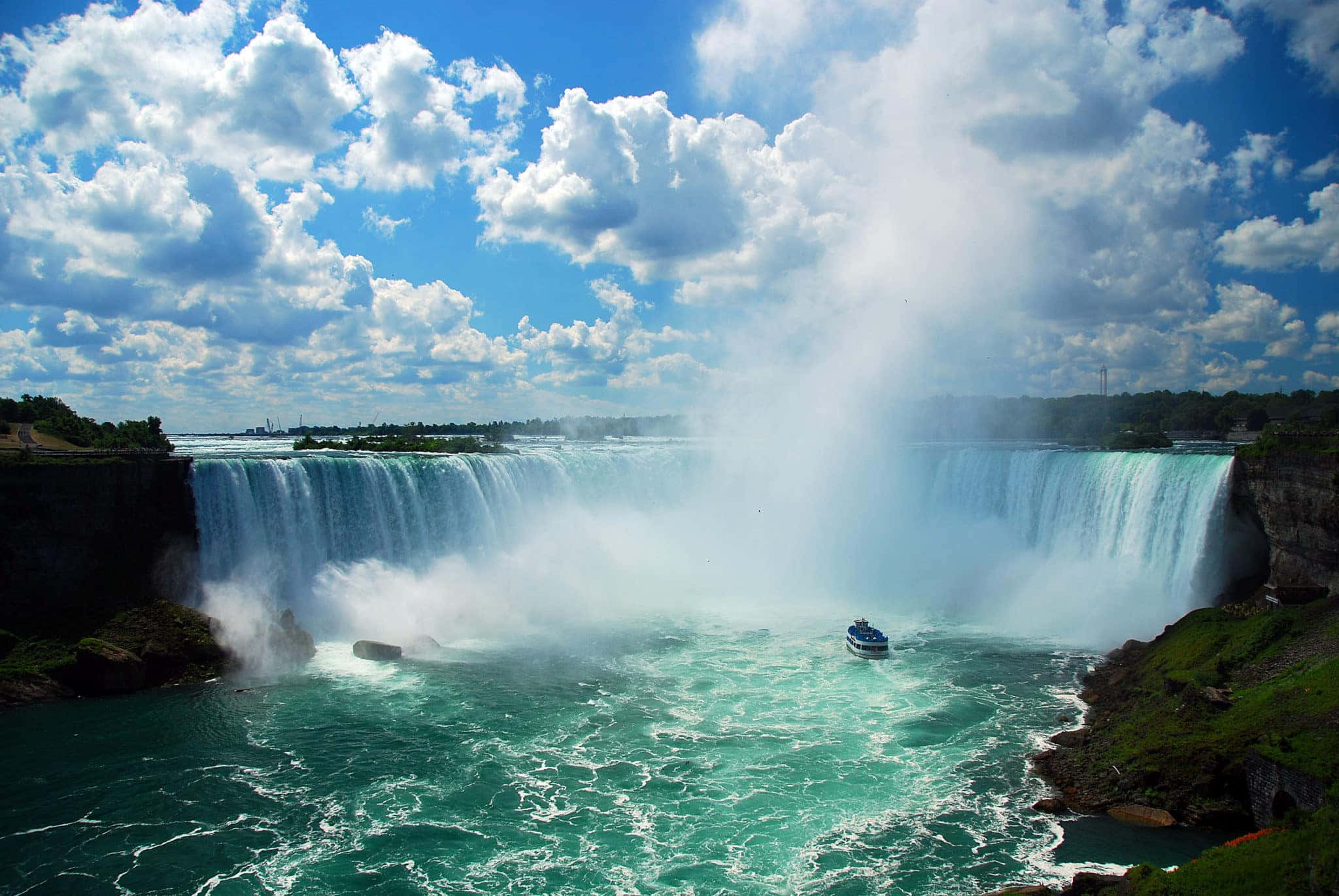 Niagara Falls 桌布 壁紙 — 在藍天白雲下，一道雄偉的寬闊瀑布傾瀉入碧綠的河流。