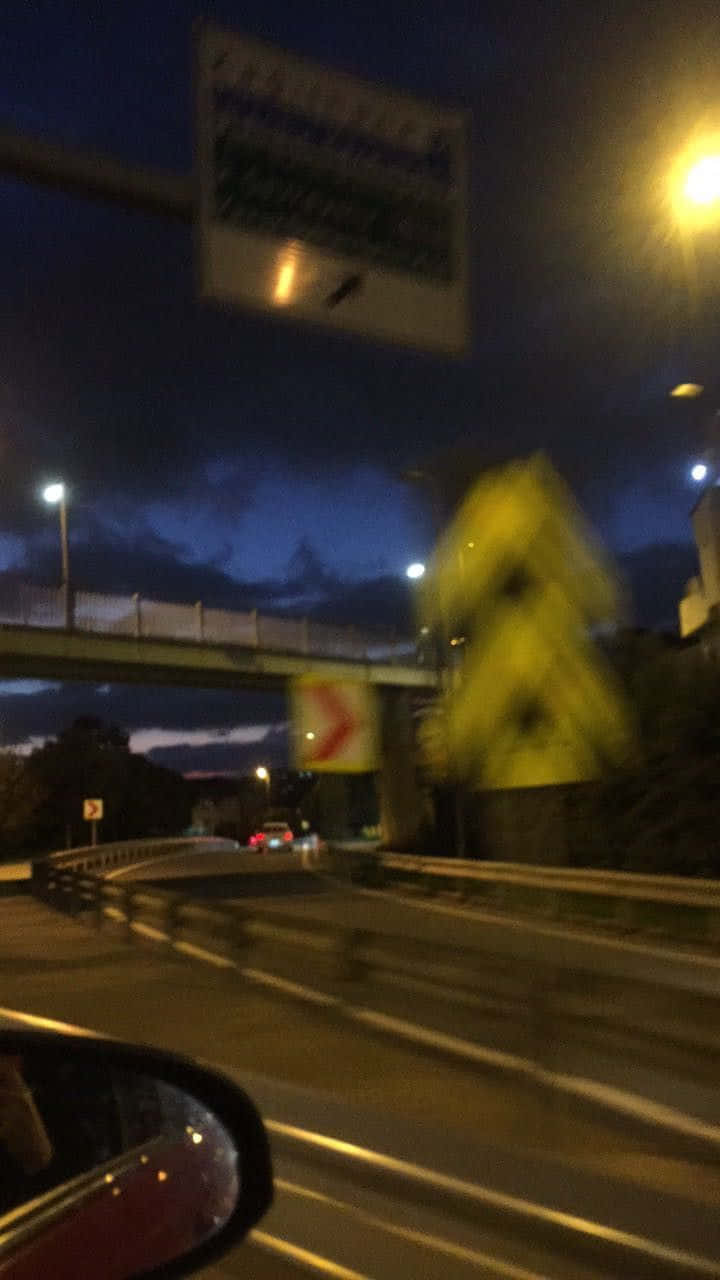 Road 桌布 壁紙 — 在街燈下的高速公路上模糊的夜間駕駛，帶有黃色道路標誌和行車天橋在移動中。