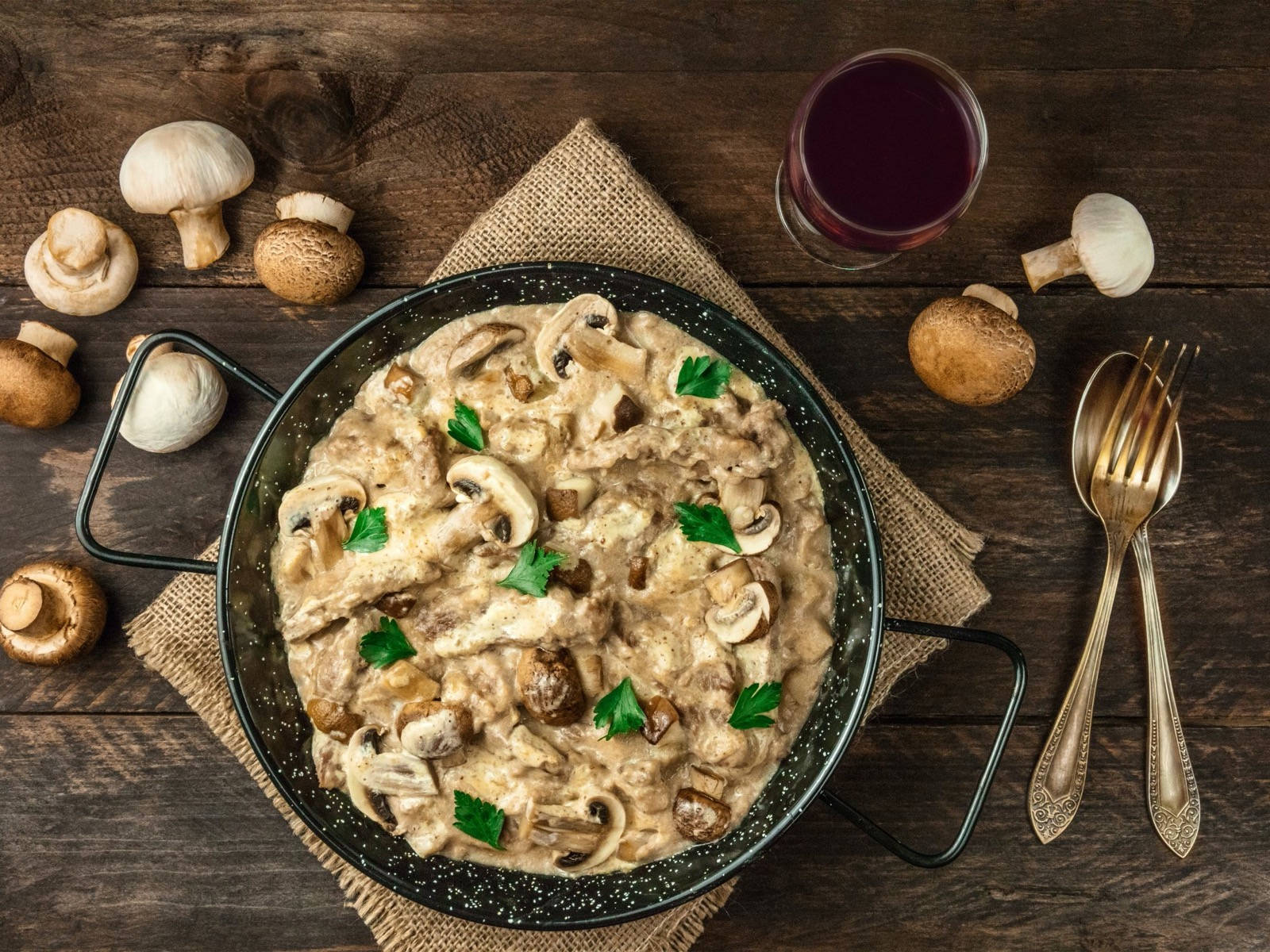 mushrooms 桌布 壁紙 — 在質樸的木桌上，斑點鍋中的奶油蘑菇醬配新鮮歐芹，散落的蘑菇和一杯紅酒。