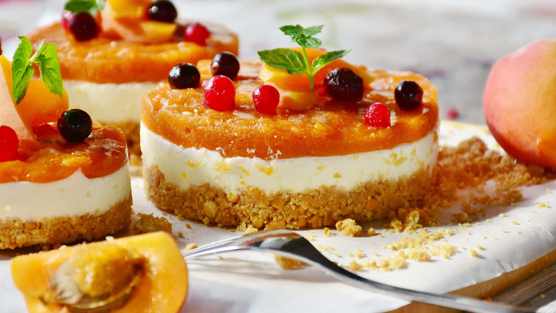 Spring Desserts 桌布 壁紙 — 在質樸的木桌上，美味的蜜桃起司蛋糕配上新鮮莓果和薄荷葉。