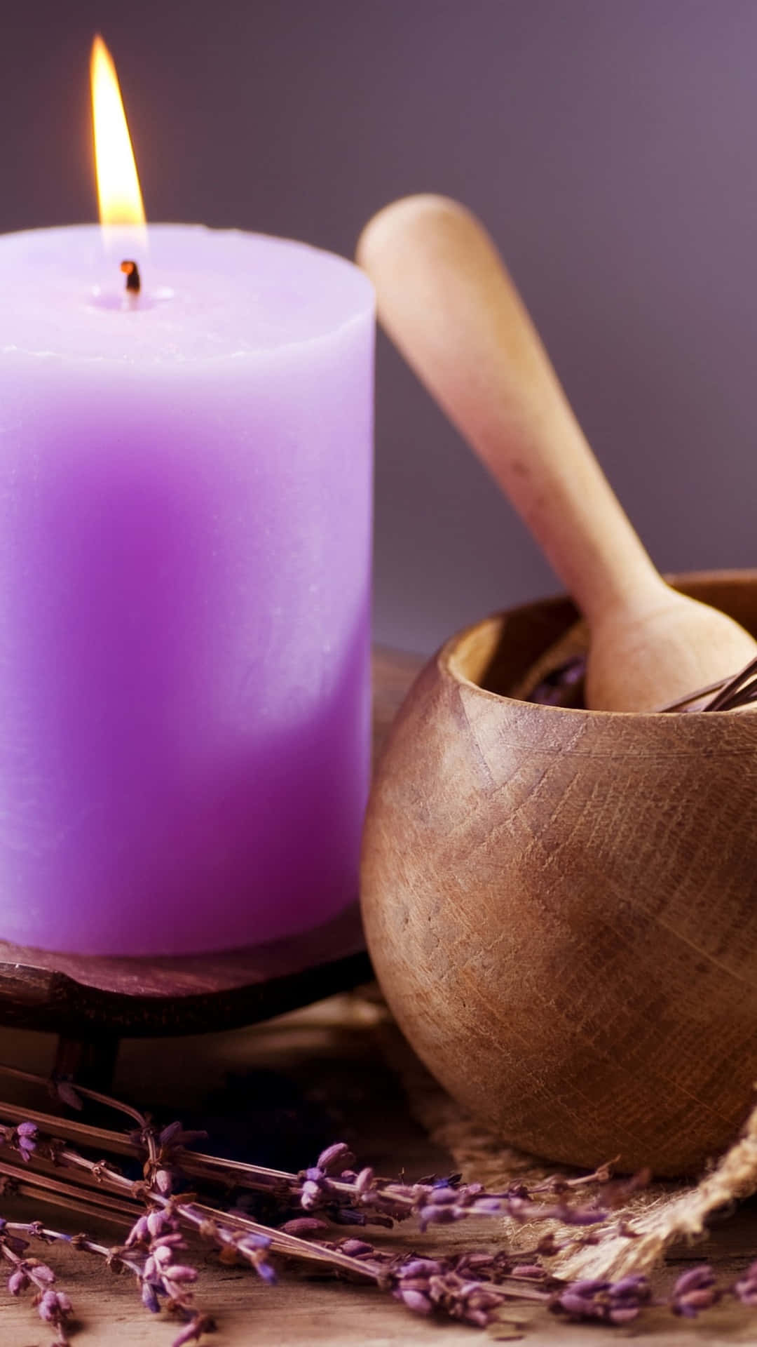 Reiki 桌布 壁紙 — 在質樸的木質表面上，一個發光的紫色蠟燭旁邊有一個木碗，裡面裝有薰衣草枝和一把湯匙。