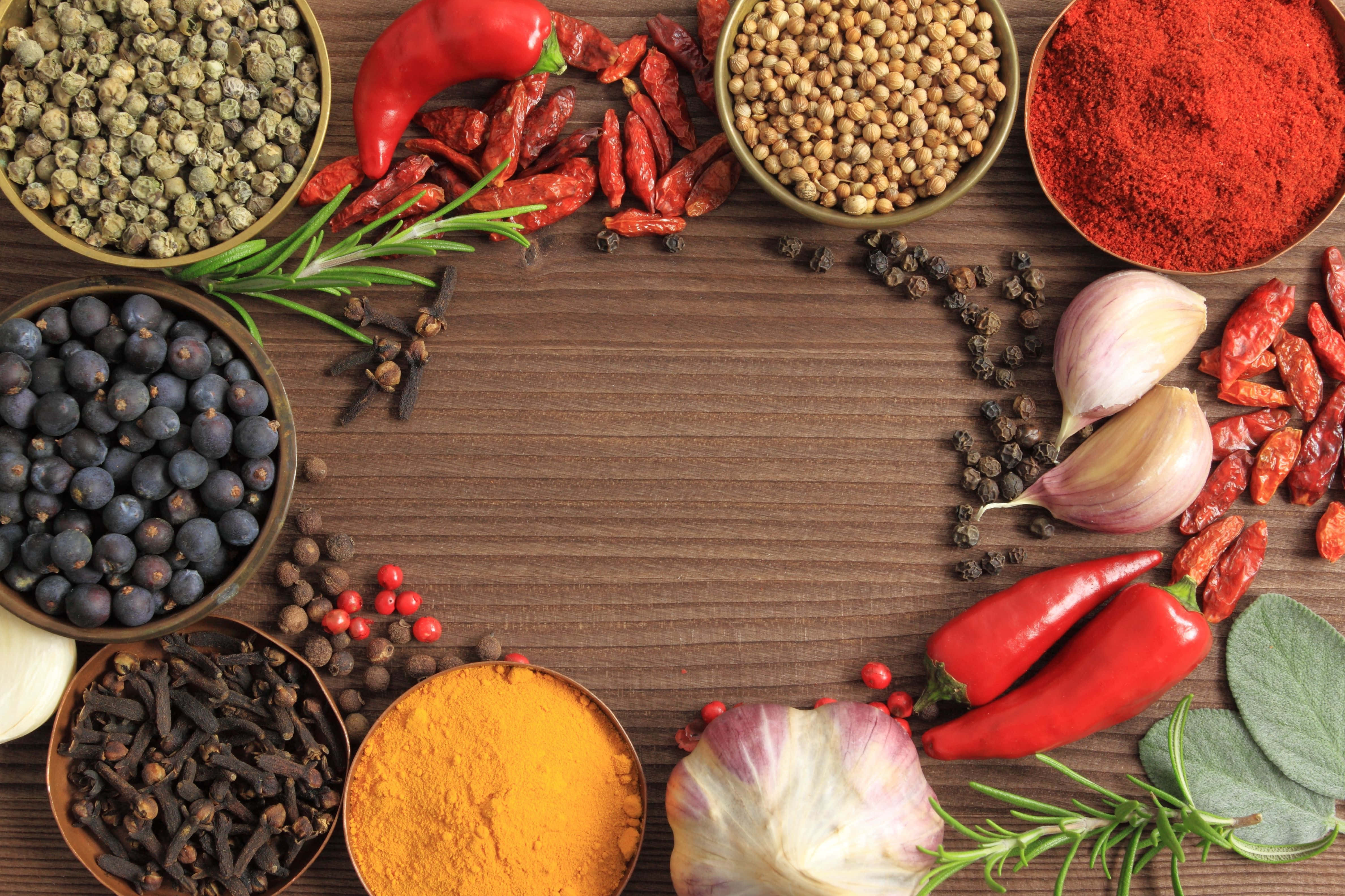 Spice 桌布 壁紙 — 在質樸的木質表面上，辣椒、薑黃和迷迭香等香料和香草以鮮豔的圓形排列。