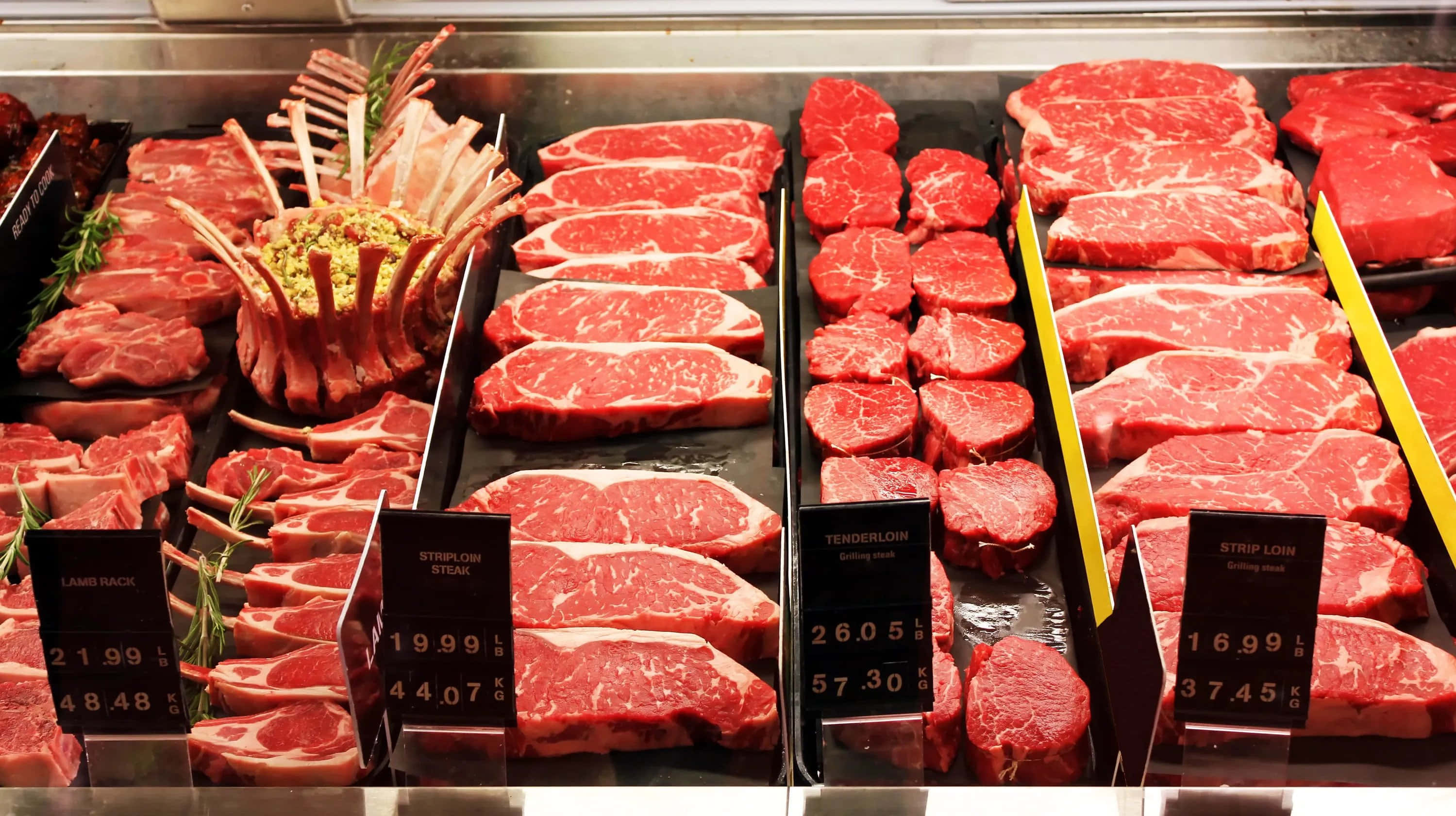 meat 桌布 壁紙 — 在超市冷藏肉類區整齊排列的新鮮生牛肉切塊，附有價格標籤，色彩鮮明。