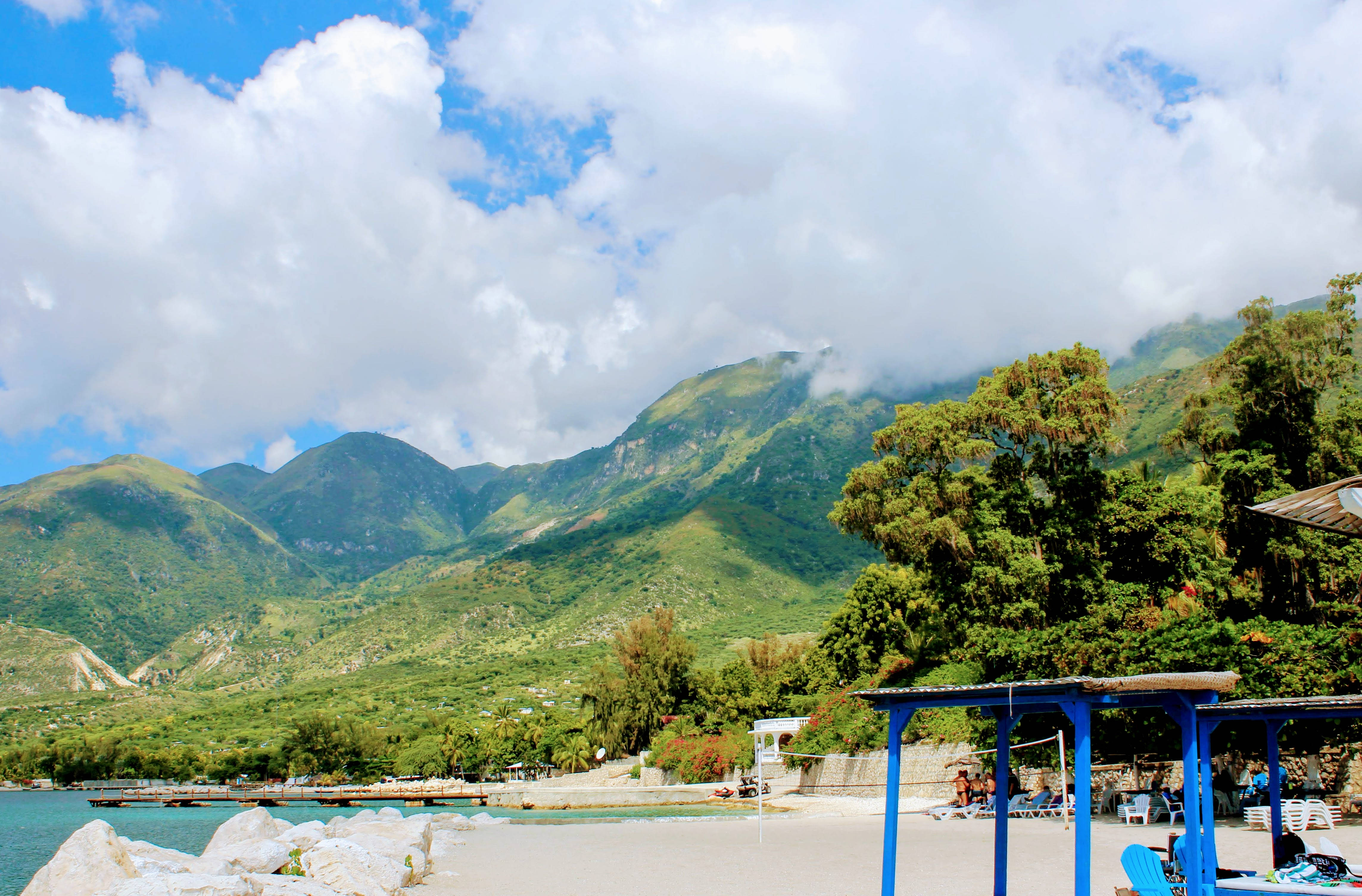 Haiti 桌布 壁紙 — 在部分多雲的天空下，一個寧靜的熱帶海灘，擁有碧綠的海水和茂密的綠色山脈。