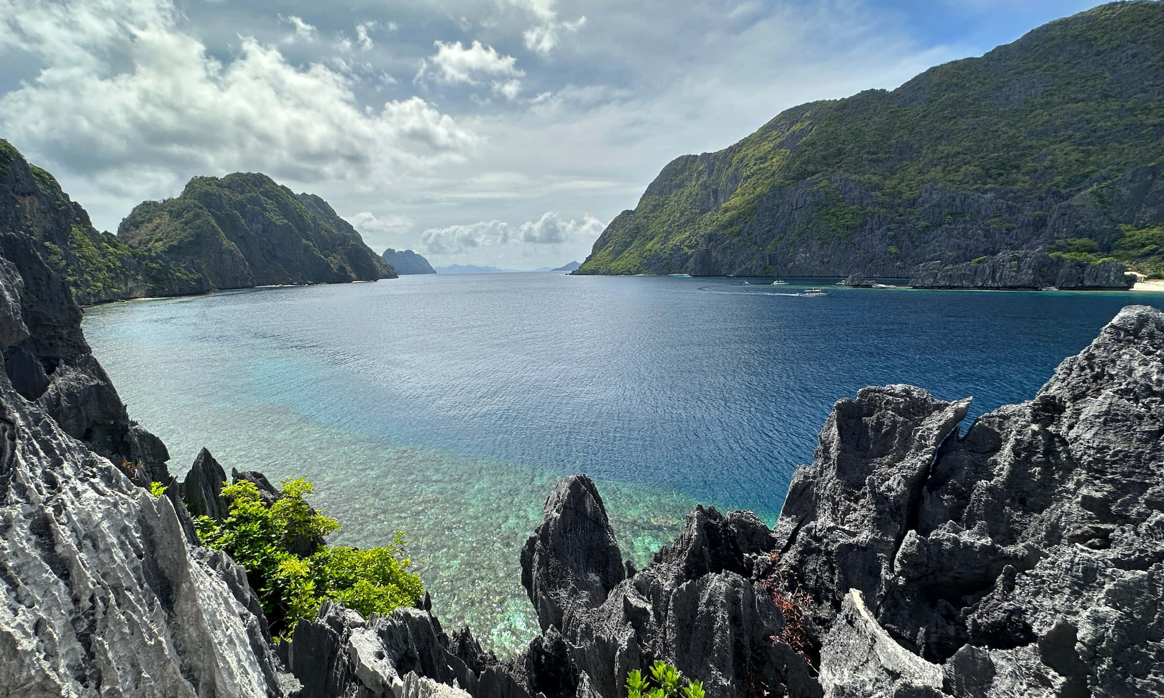 Philippines 桌布 壁紙 — 在部分多雲的天空下，一個碧綠色的潟湖 nestled 在崎嶇的石灰岩懸崖之間，景色令人嘆為觀止。