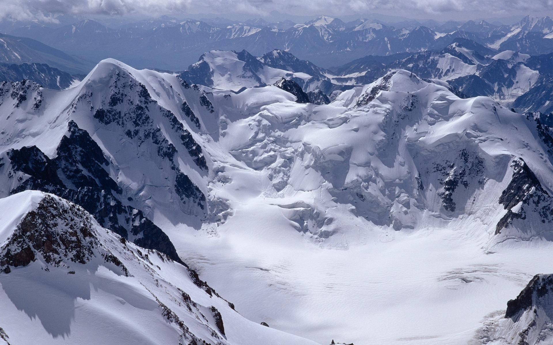 Windows 冬季 桌布 壁紙 — 在陰天下一覽無遺的雪峰和冰川的航拍美景。