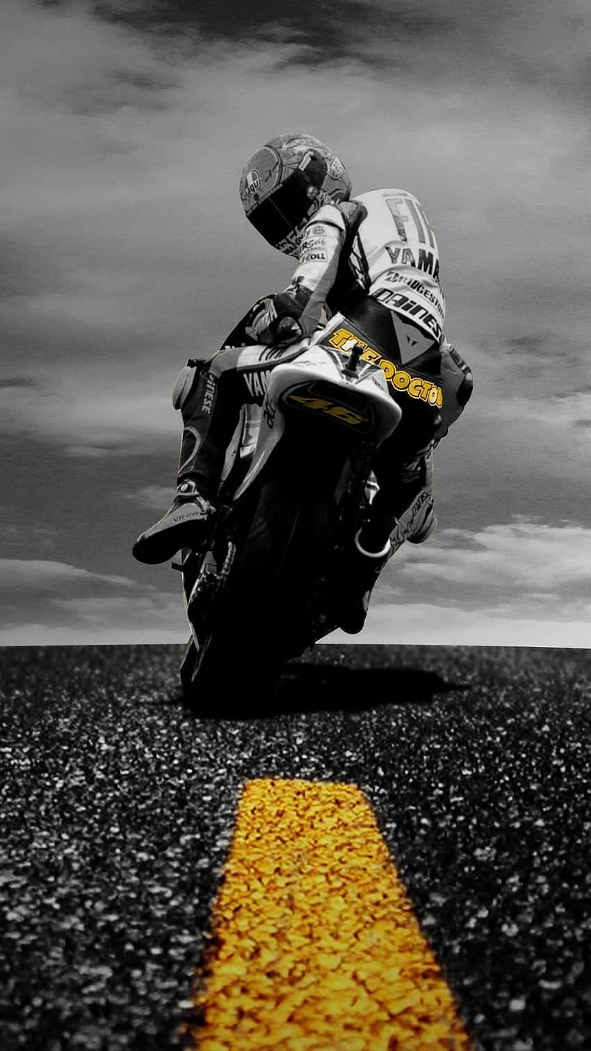 Motorcycle iPhone 桌布 壁紙 — 在陰天之下，一名機車手在黑白相間的道路上，沿著鮮黃色的中央線傾斜入一個急彎。