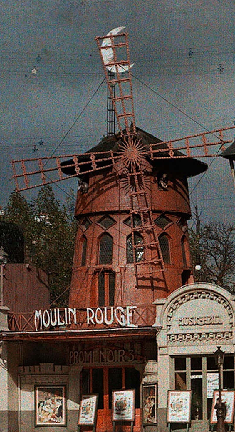moulin rouge 桌布 壁紙 — 在陰天之下，一座帶有新月頂部的復古紅色風車矗立在紅磨坊夜總會入口上方。