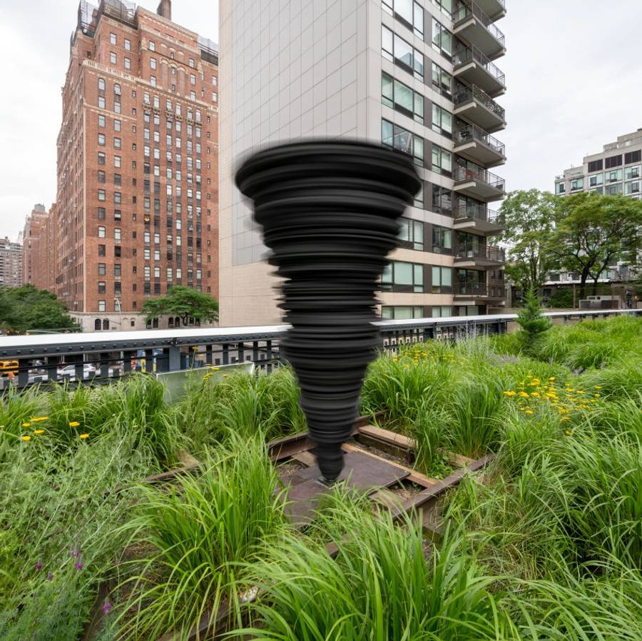 New York 桌布 壁紙 — 在陰天之下，一座黑色螺旋雕塑矗立於茂密的綠色屋頂花園中，四周環繞著高聳的城市建築。
